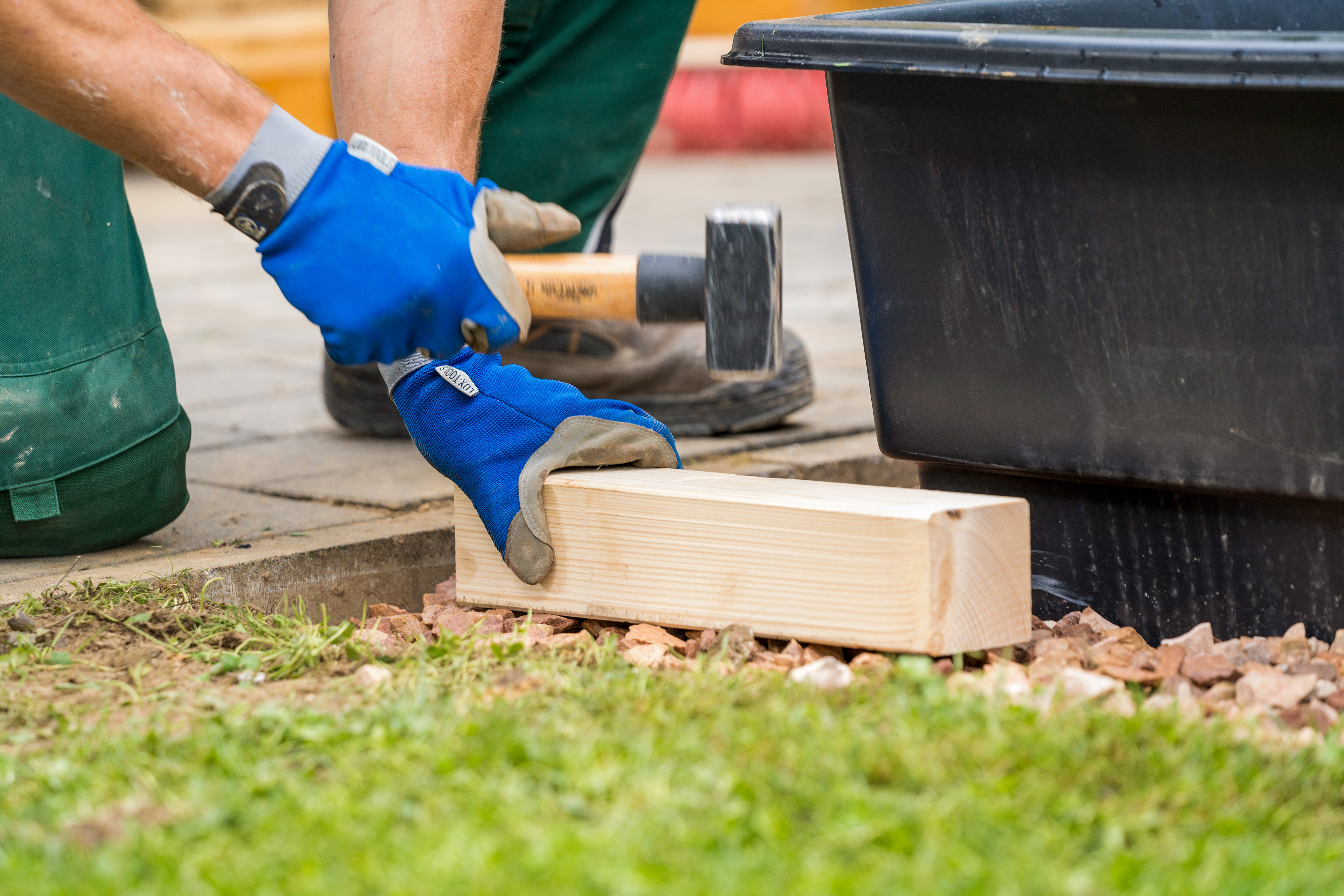 Egy barkácsoló kalapács és fahasáb segítségével tömöríti a zúzalékot.