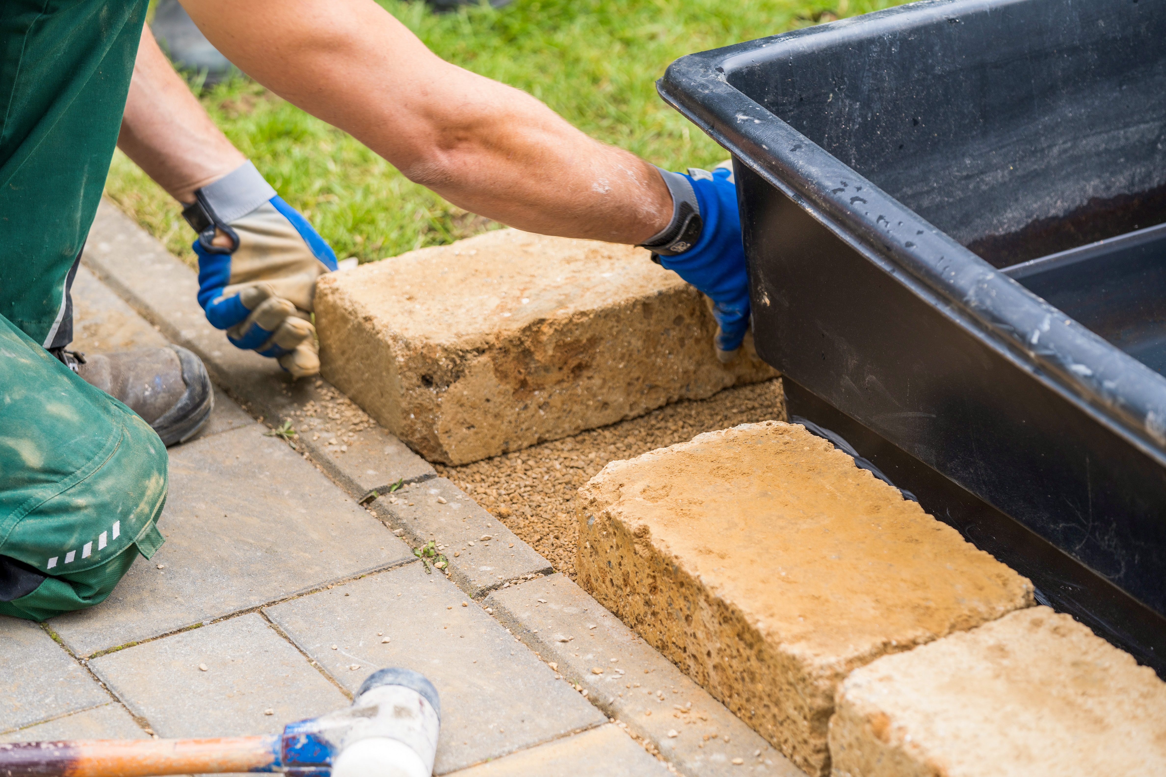 Egy barkácsoló tufakövet helyez el a tómeder szegélyeként.
