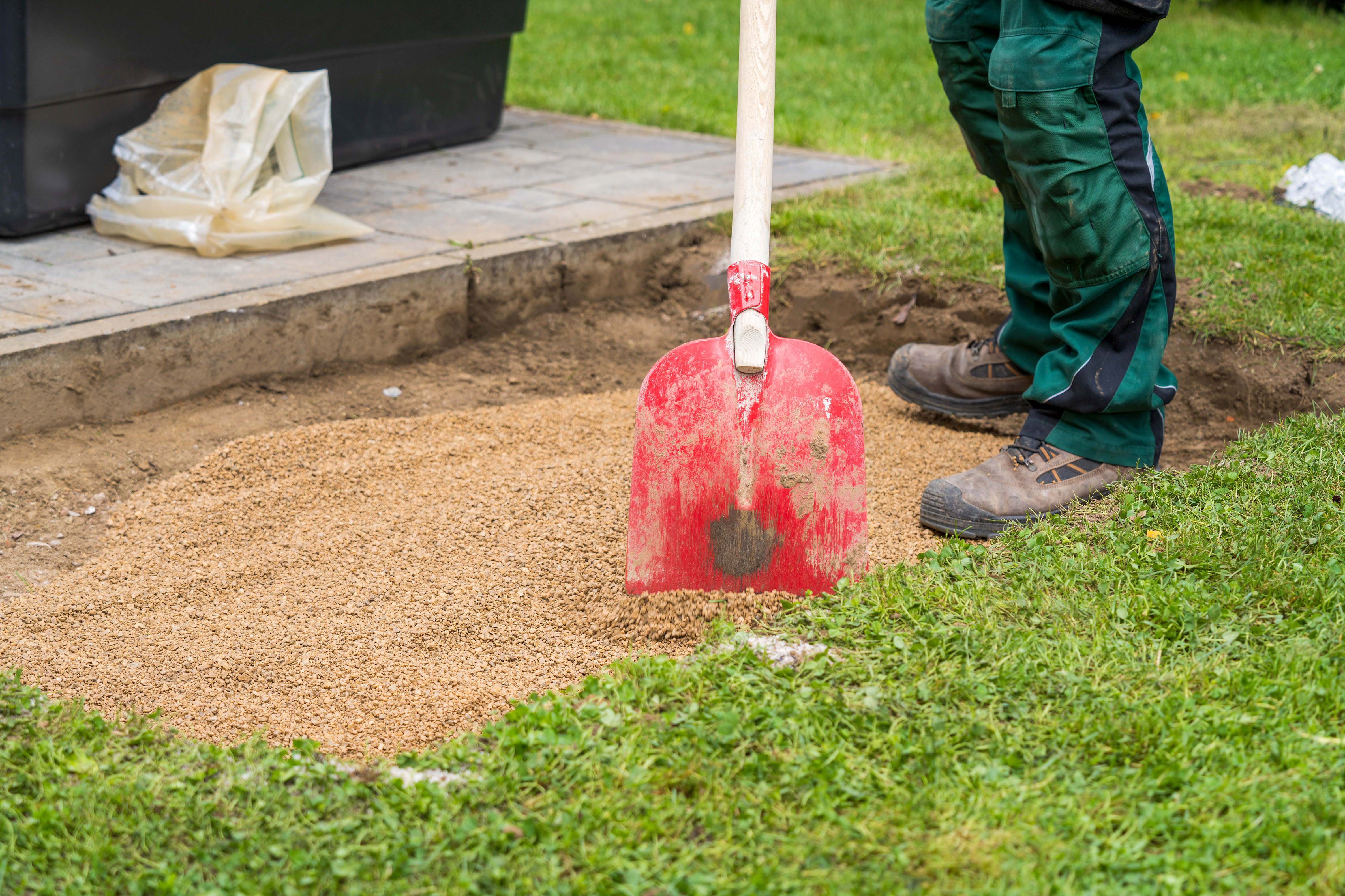 Egy barkácsoló lapáttal teríti szét a zúzalékot a gödörben