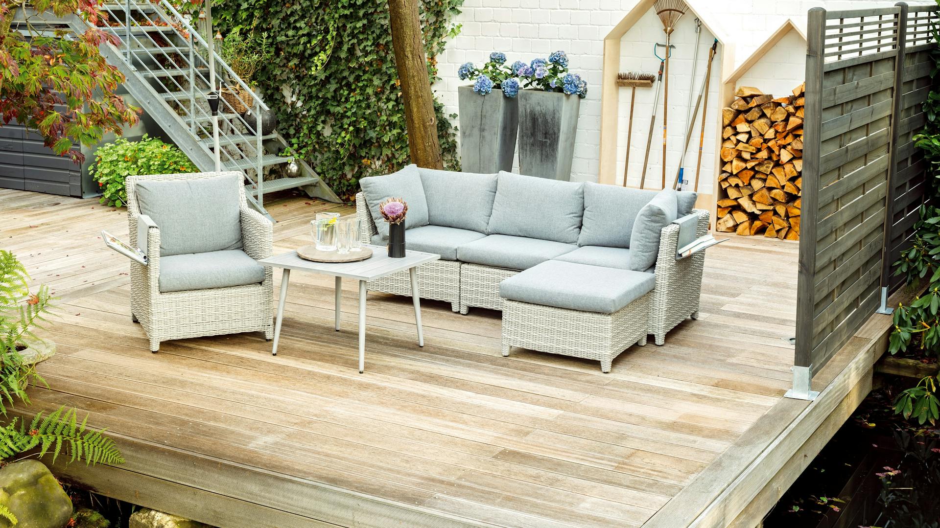 Terrazza in legno con pannello fendivista e mobili da giardino