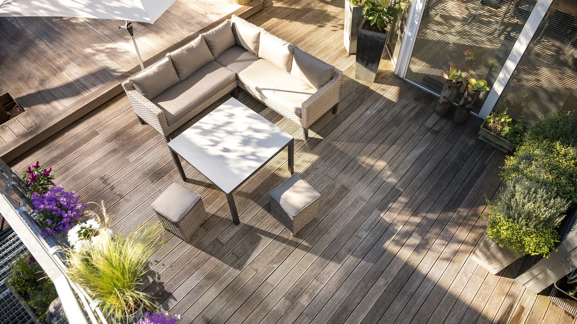 Foto di una terrazza vista dall’alto con assi di legno, mobili da giardino e piante