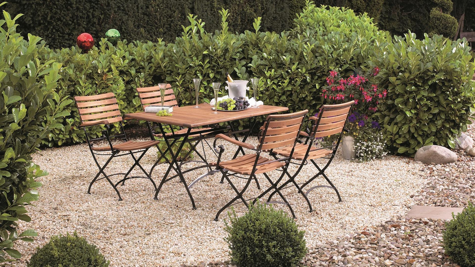 Kiesterrasse mit Granit Platten und Sitzgelegenheit im Garten.