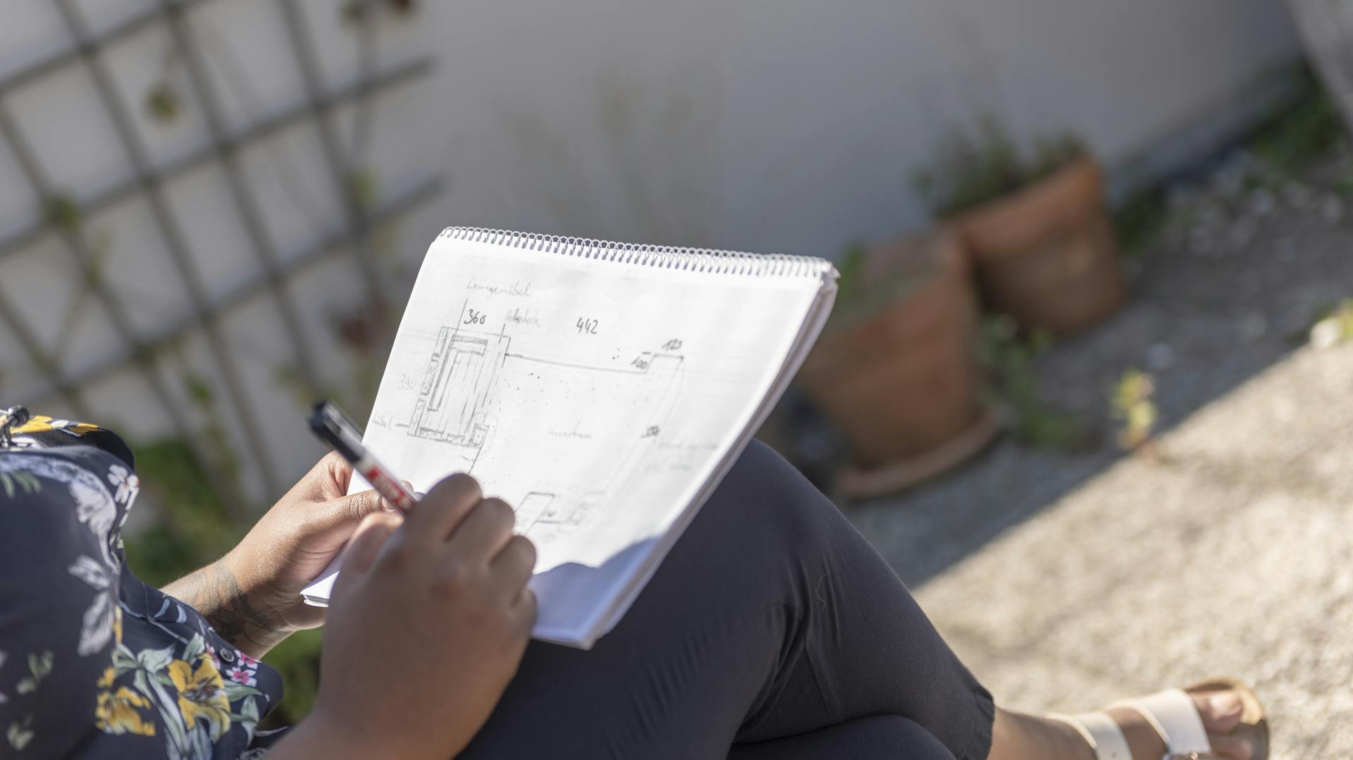 Frau, die eine Terrasse auf einem Stück Papier skizziert