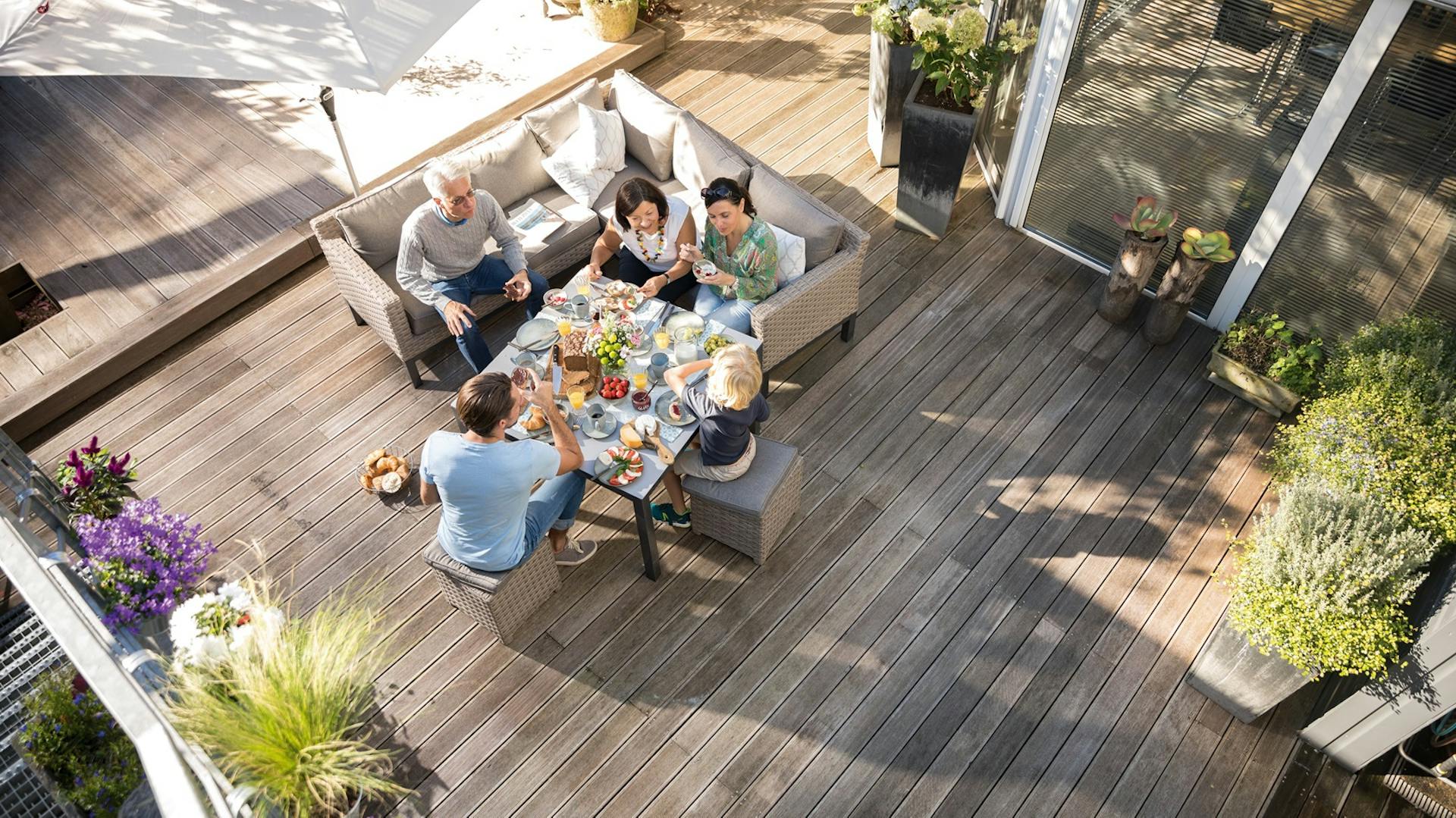 Luftaufnahme einer Familie, die auf einer Terrasse mit Holzdielen sitzt