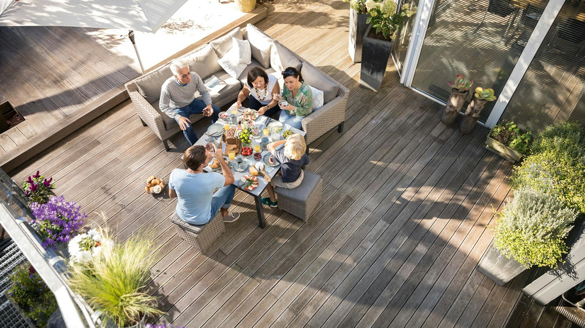 Luftaufnahme einer Familie, die auf einer Terrasse mit Holzdielen sitzt