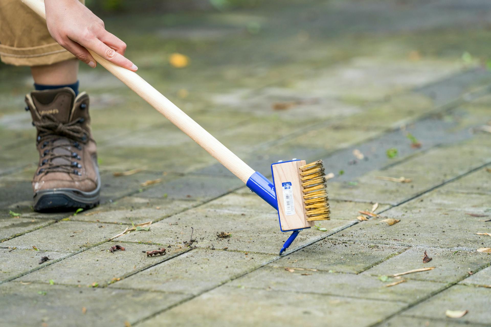 Con una spazzola per giunti vengono pulite le giunture tra le piastre per terrazza.