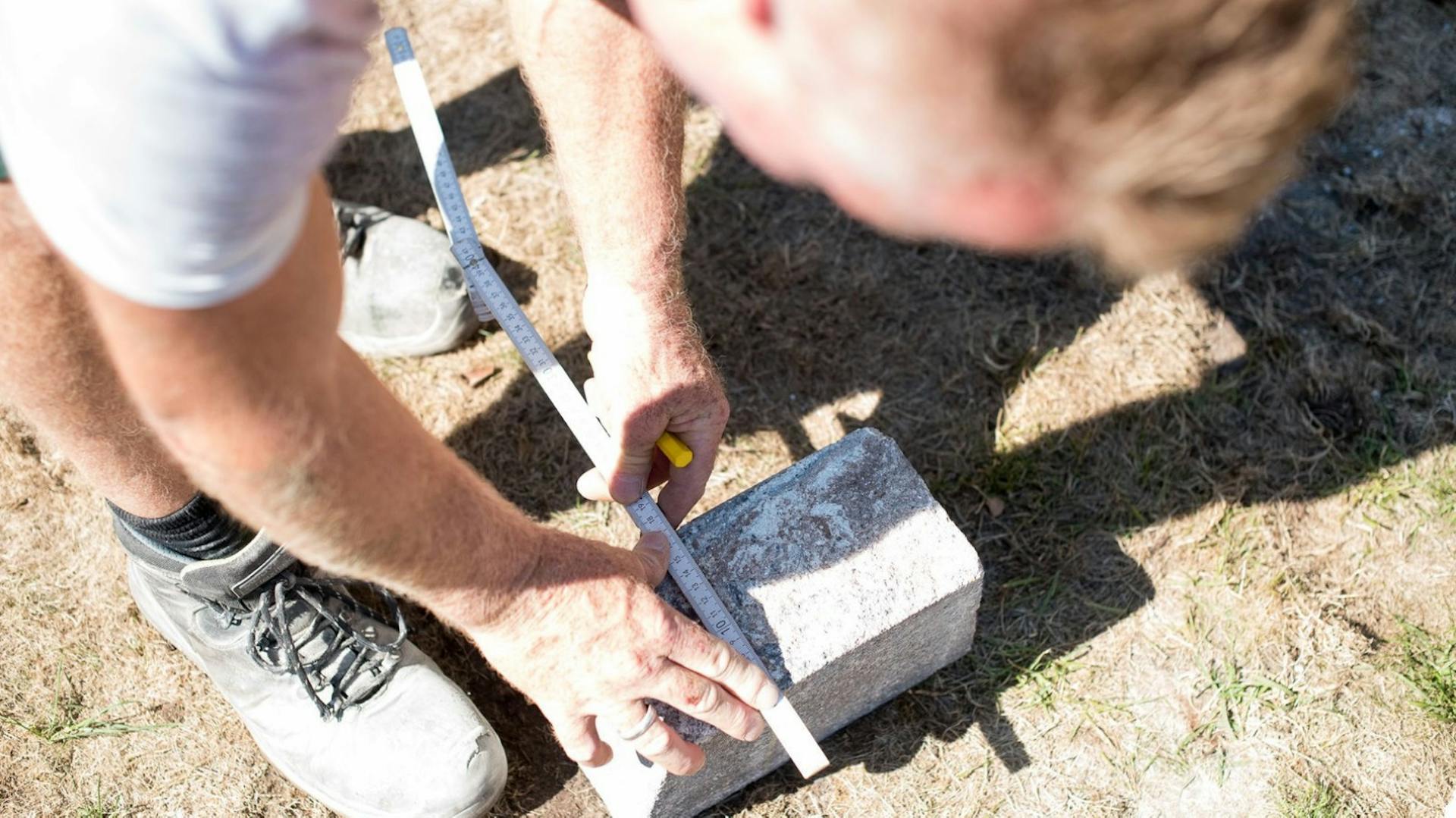 Mann zeichnet die Schnittstelle auf einen Terrassenstein.