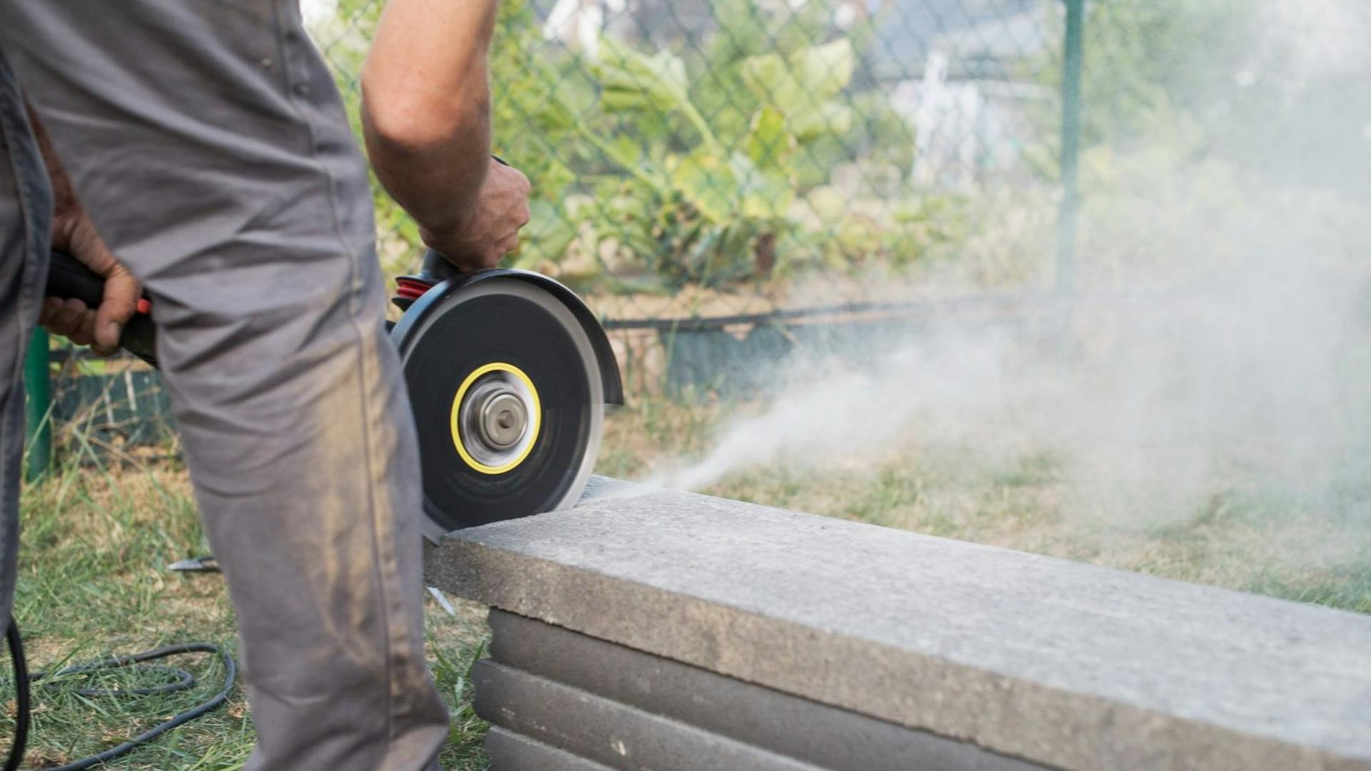 Heimwerker schneidet Terrassenplatte mit einem Winkelschleifer.