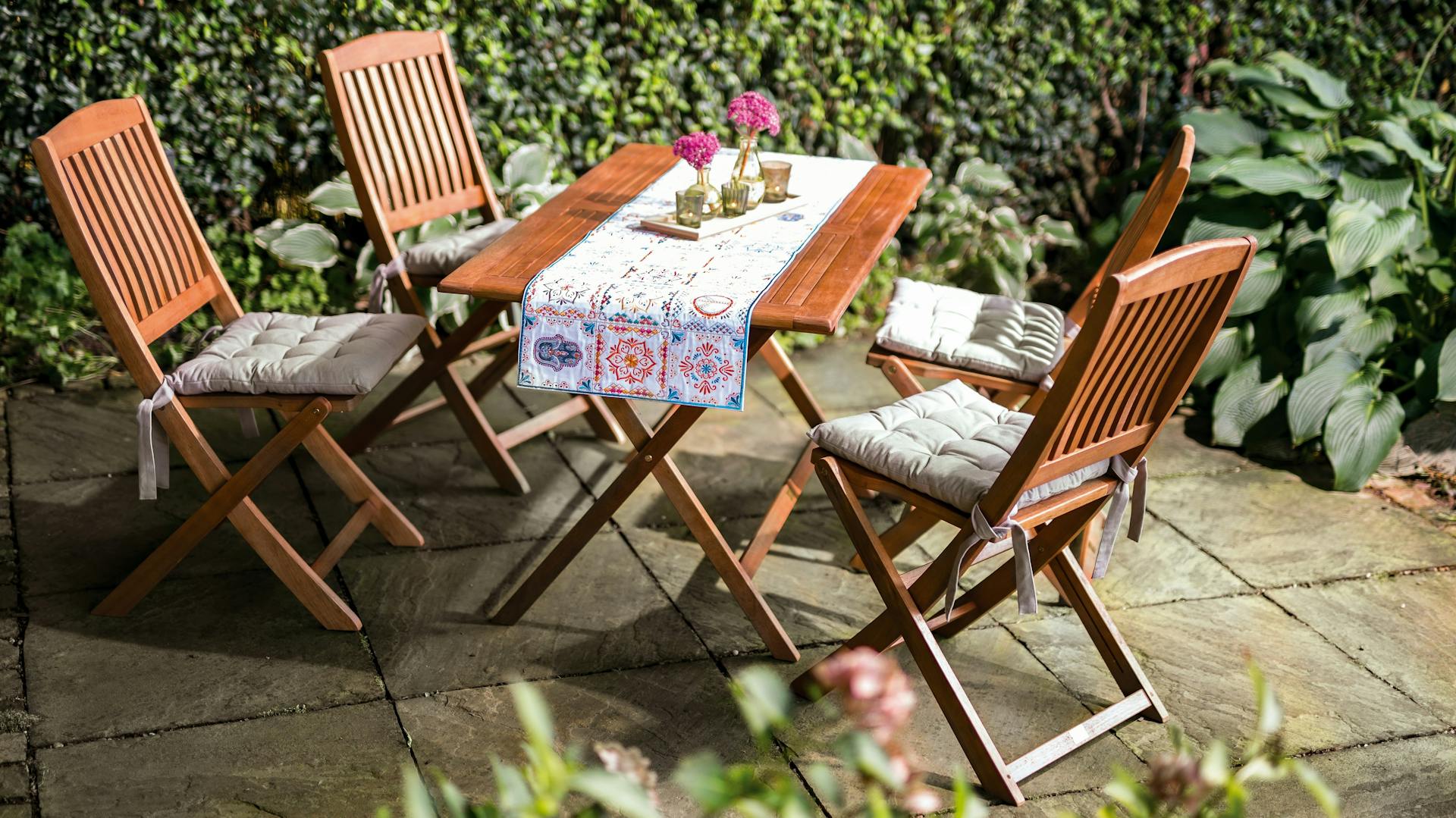 Sitzgruppe aus Holz auf Terrasse mit natürlich wirkenden Steinplatten