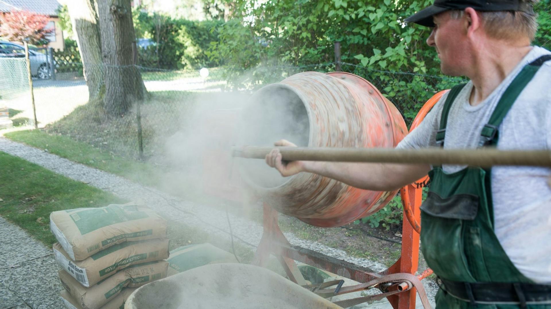 Muž hádže cement do miešačky