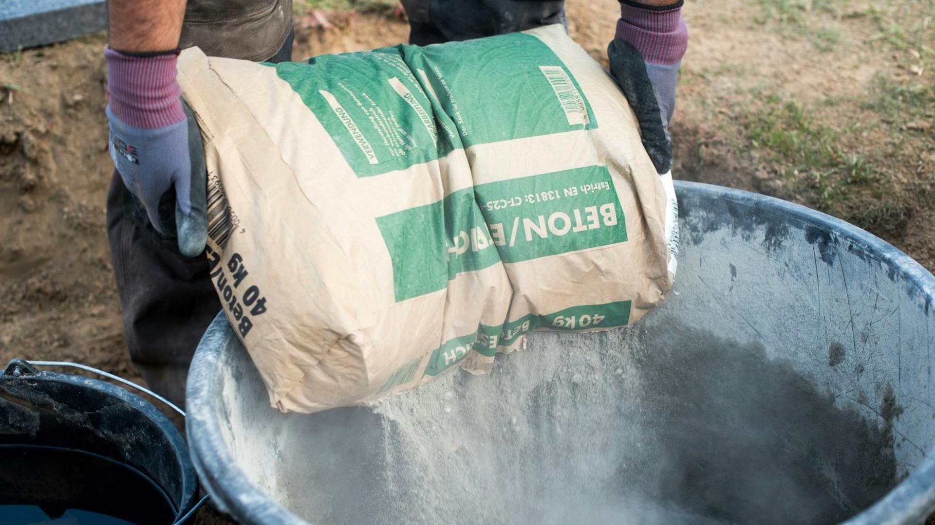 Mann befüllt Eimer mit Beton