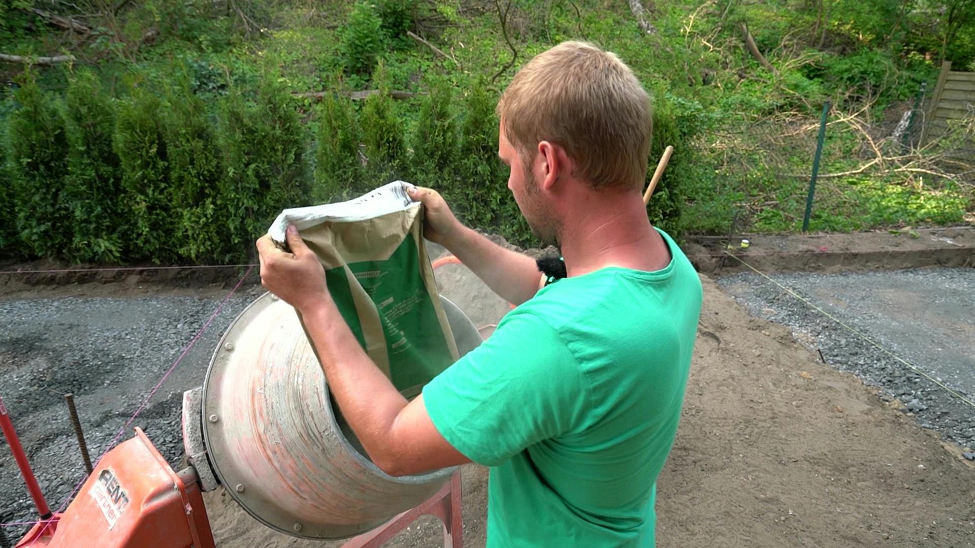 Mann befüllt Betonmischer mit Zement