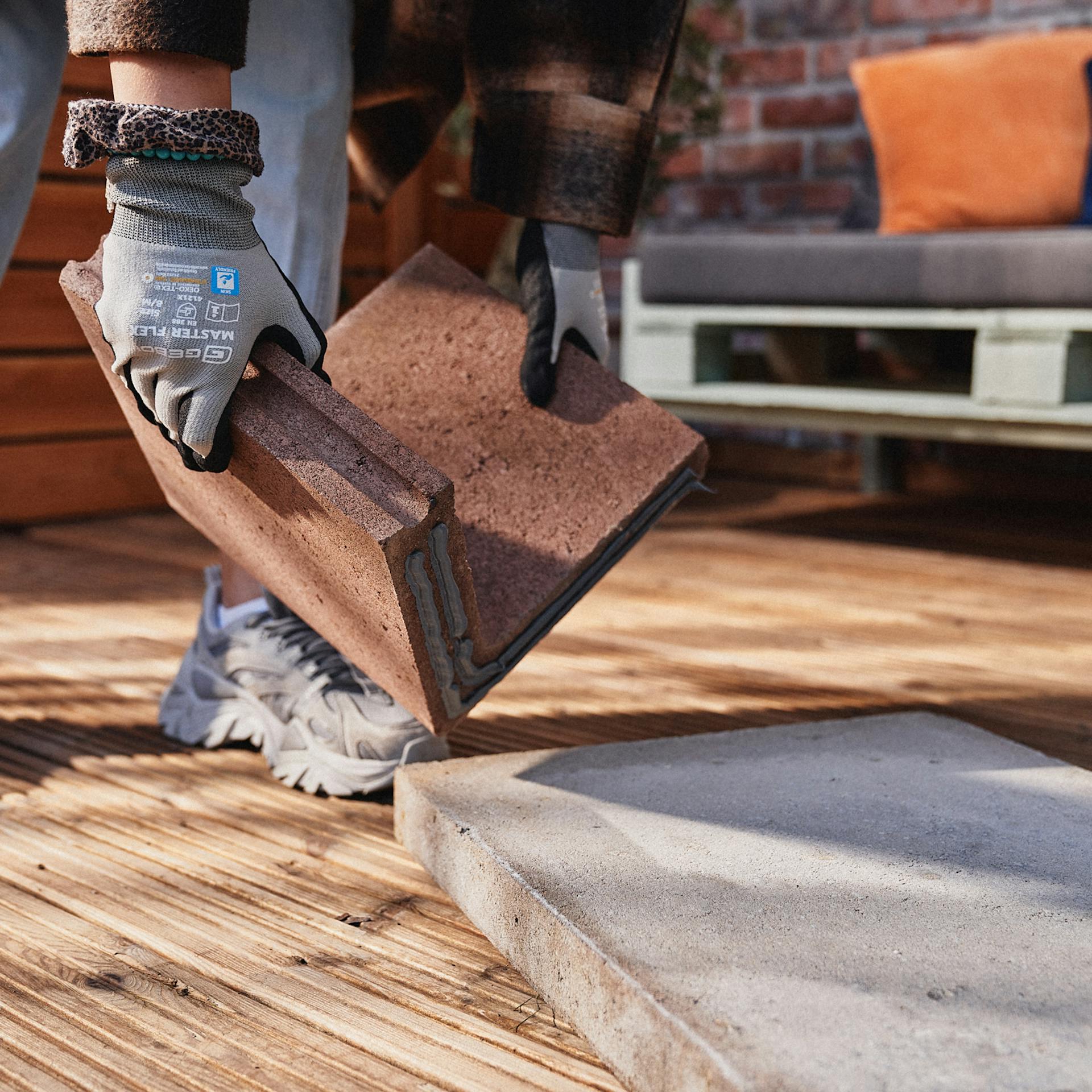 Remeselníčka zdvihne zlepenú stranu základného kameňa na terasovú dosku.