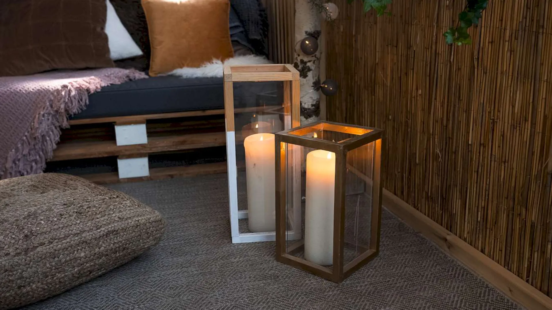 Zwei DIY-Windlichter stehen vor einer Palettencouch auf einer Terrasse