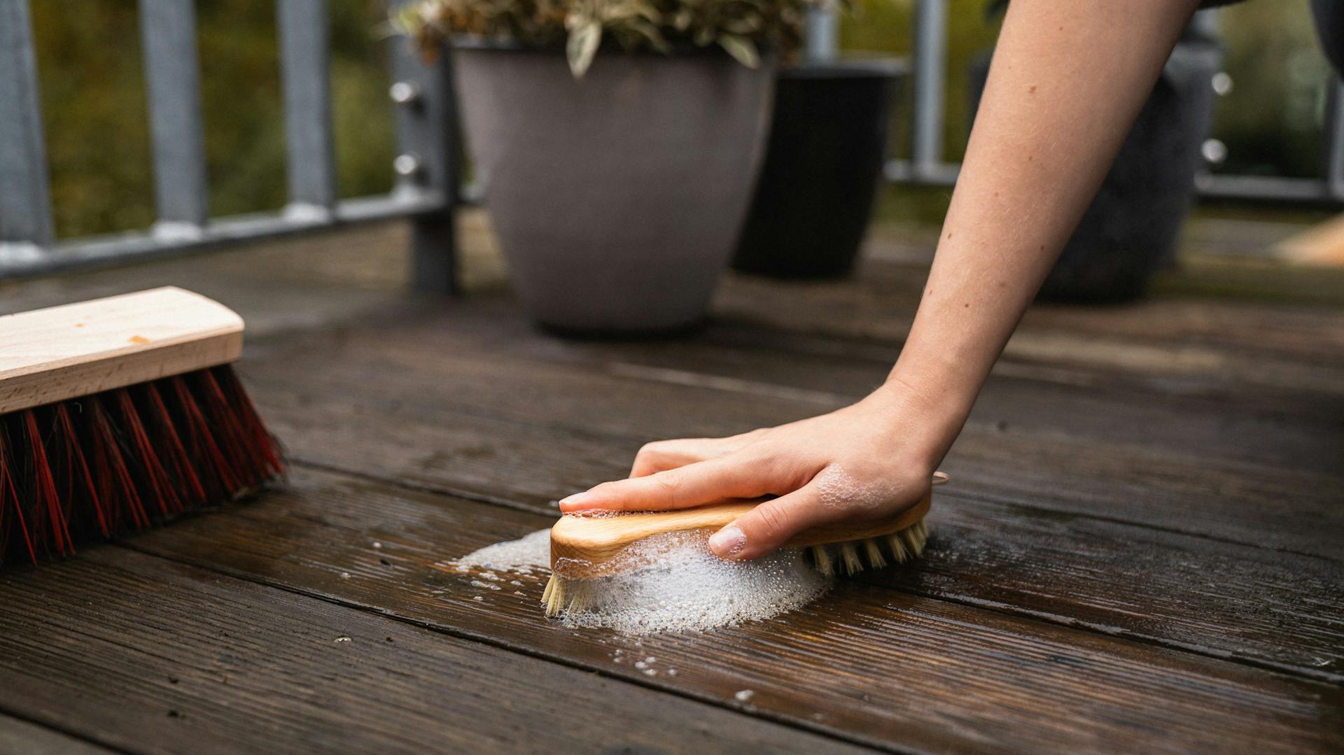 Terrassenboden wird mit Holzbürste geschrubbt.