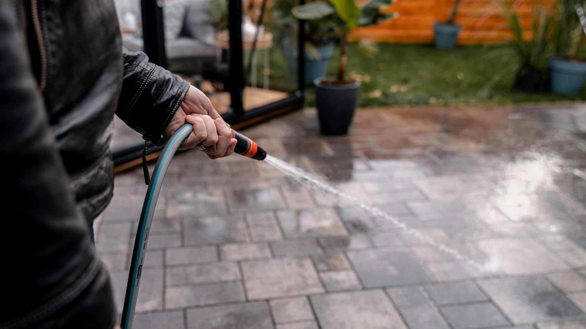 Terrasse mit mit Gartenschlauch und Wasser gereinigt