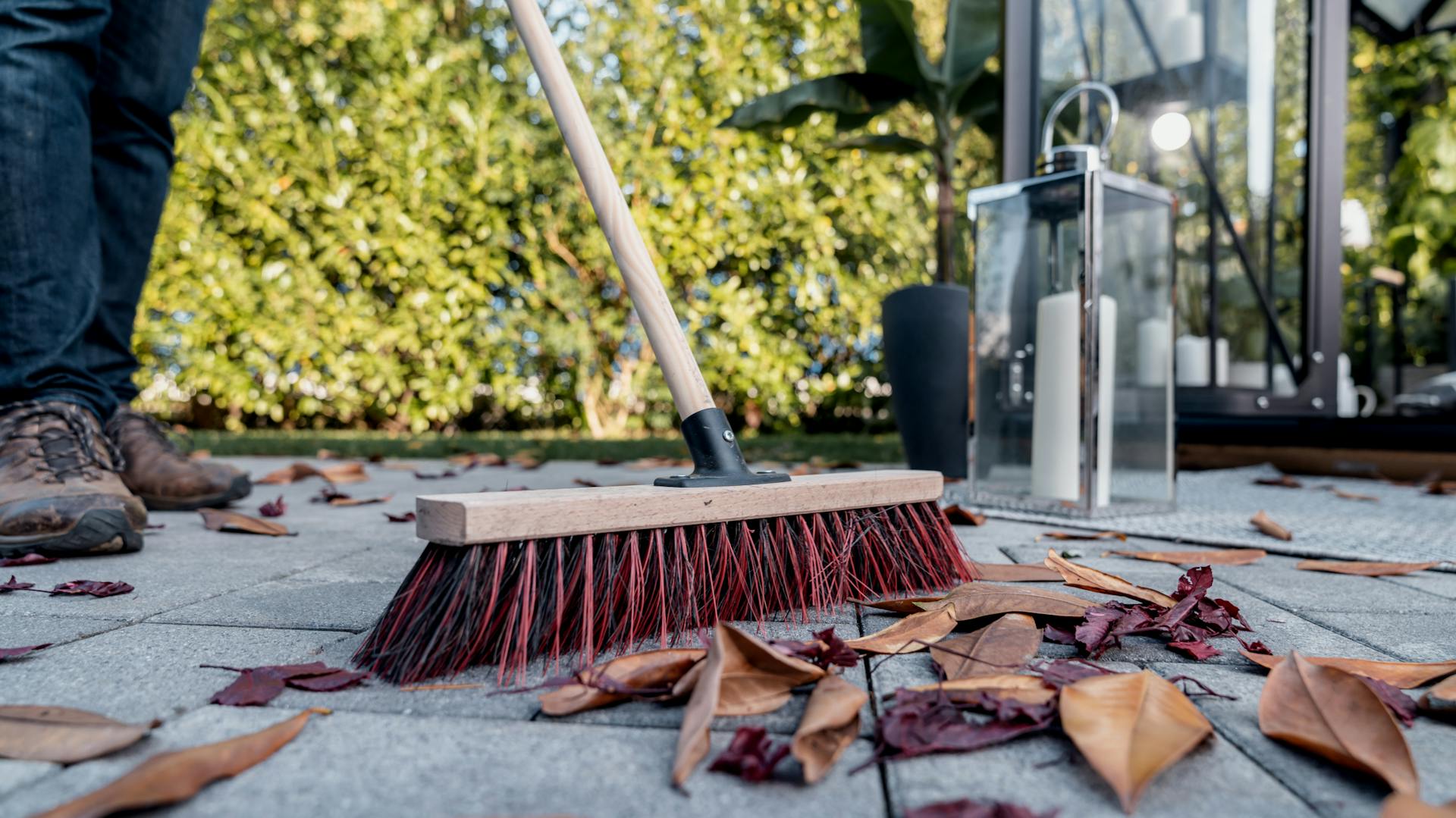 Laub auf Terrasse wird zusammengekehrt