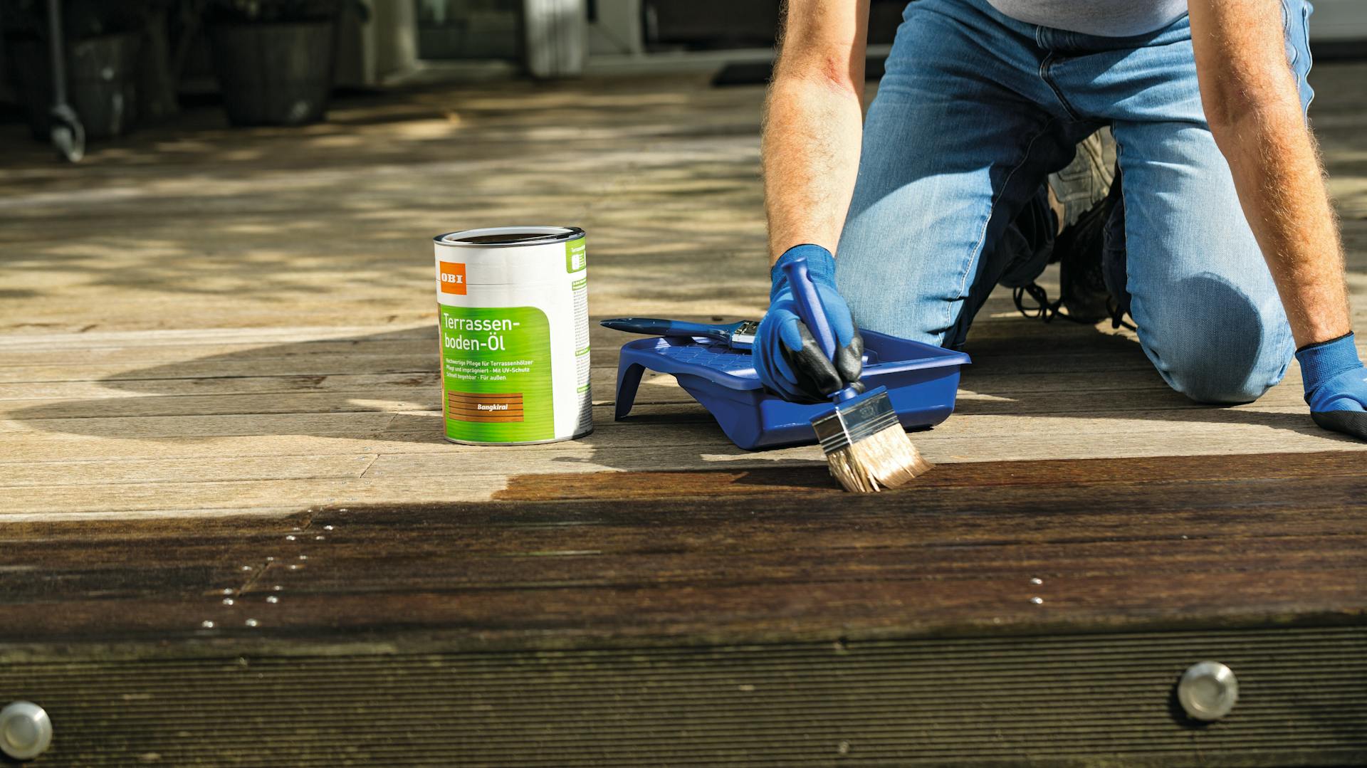 Person trägt Terrassen-Boden-Öl auf Terrassendielen auf.