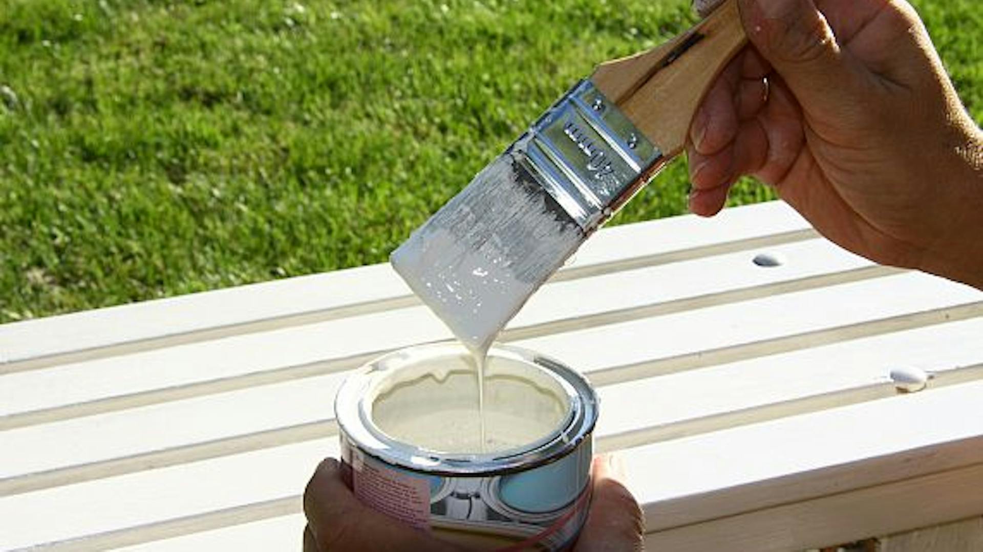 L'artigiano tiene una lattina di vernice e un pennello.