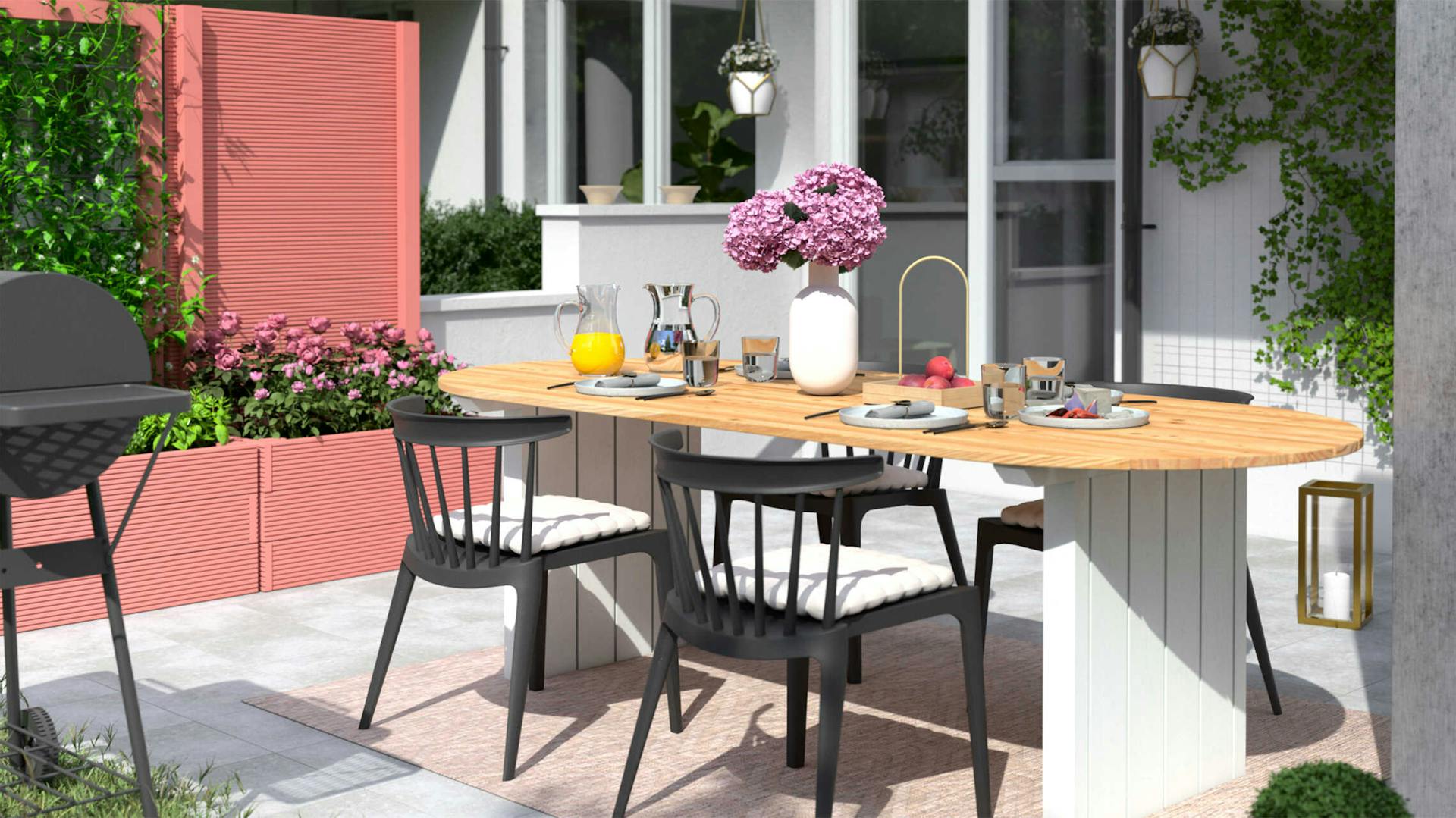 Gartentisch Emilia steht auf einer hellen Terrasse, wo das Hochbeet Alfred in einem pastellrot als Sichschutz aufgestellt worden ist.