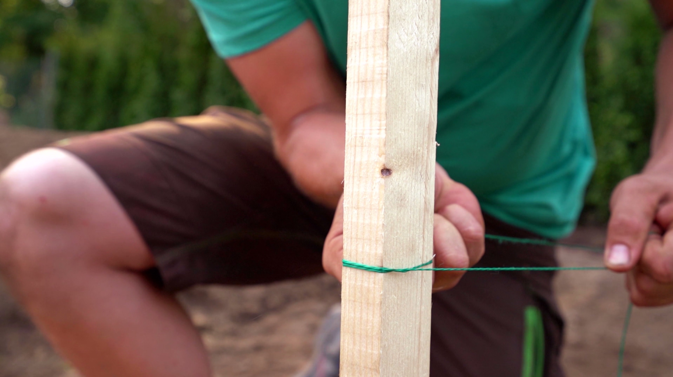 Foto eines Holzpfahls mit Richtschnur, die von einem Heimwerker gezogen wird