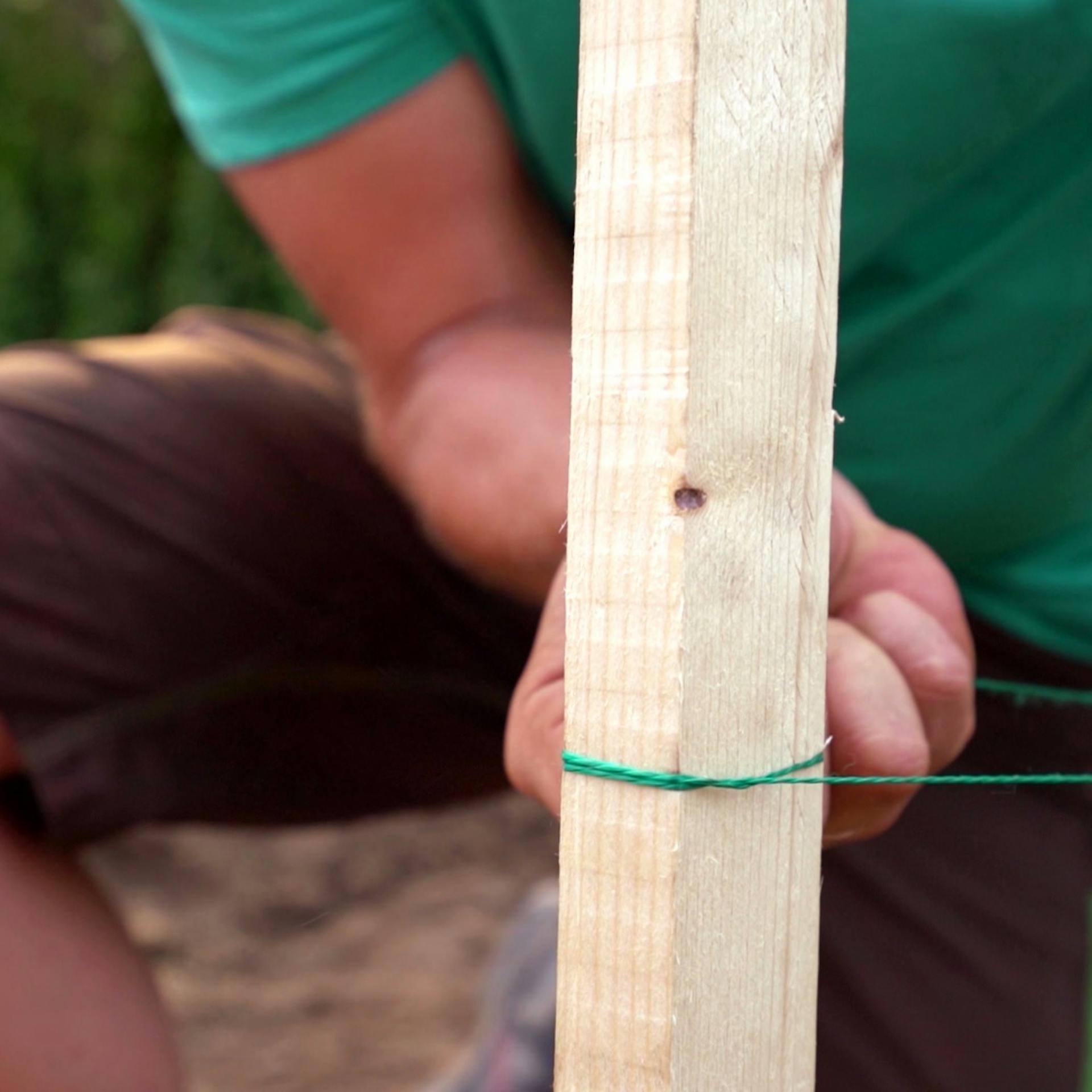 Foto eines Holzpfahls mit Richtschnur, die von einem Heimwerker gezogen wird