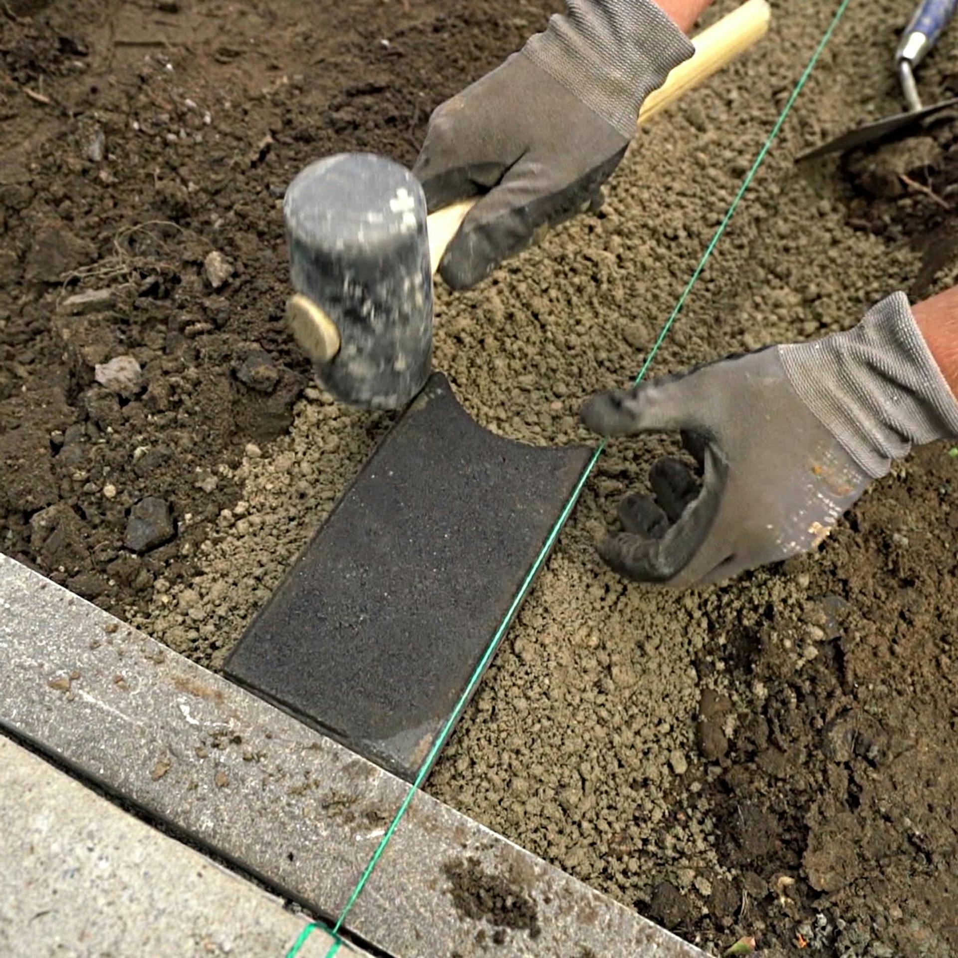 Steine für Maehkante werden gesetzt