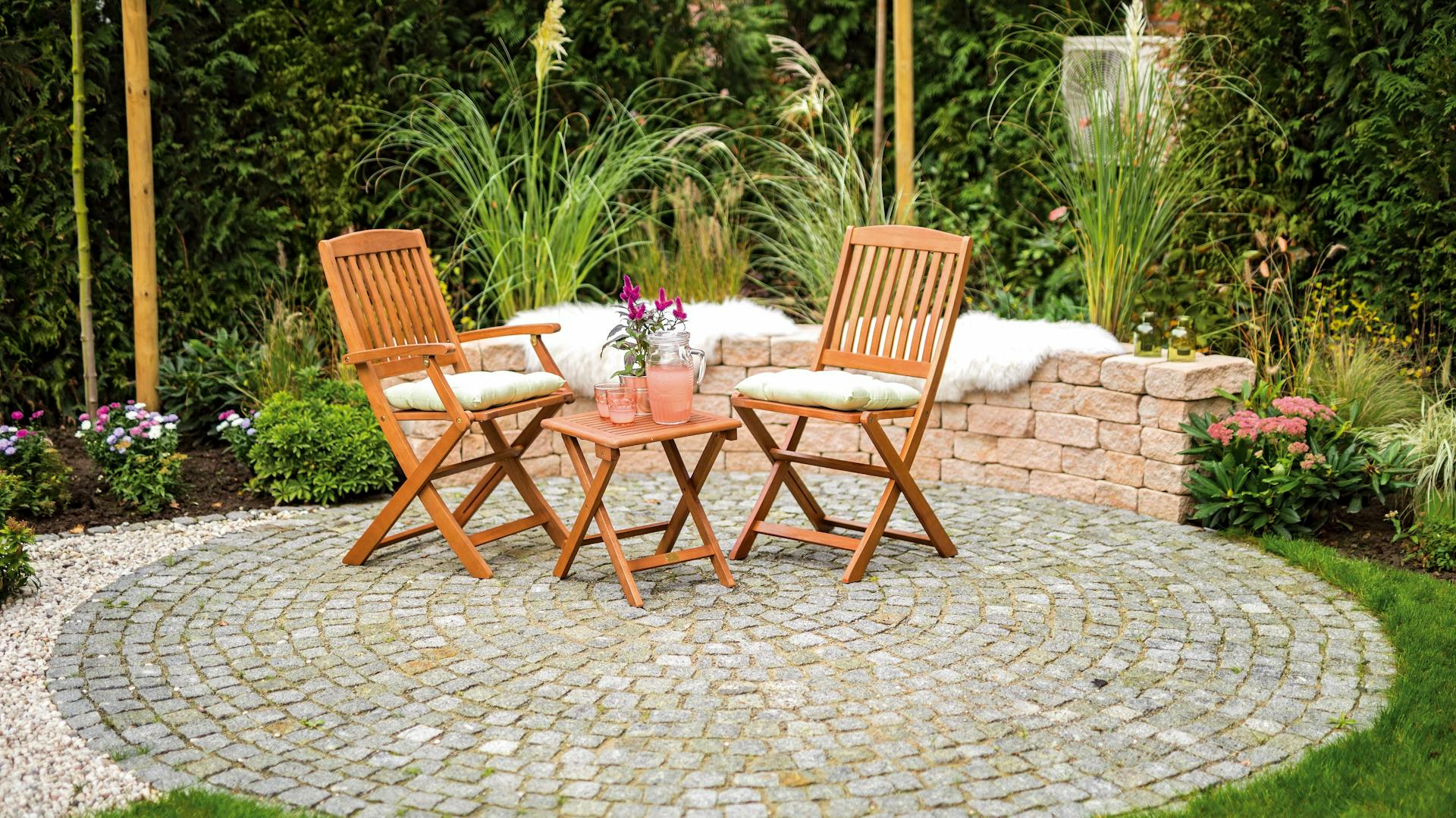 Terrasse mit Pflastersteinen und Gartenmöbeln