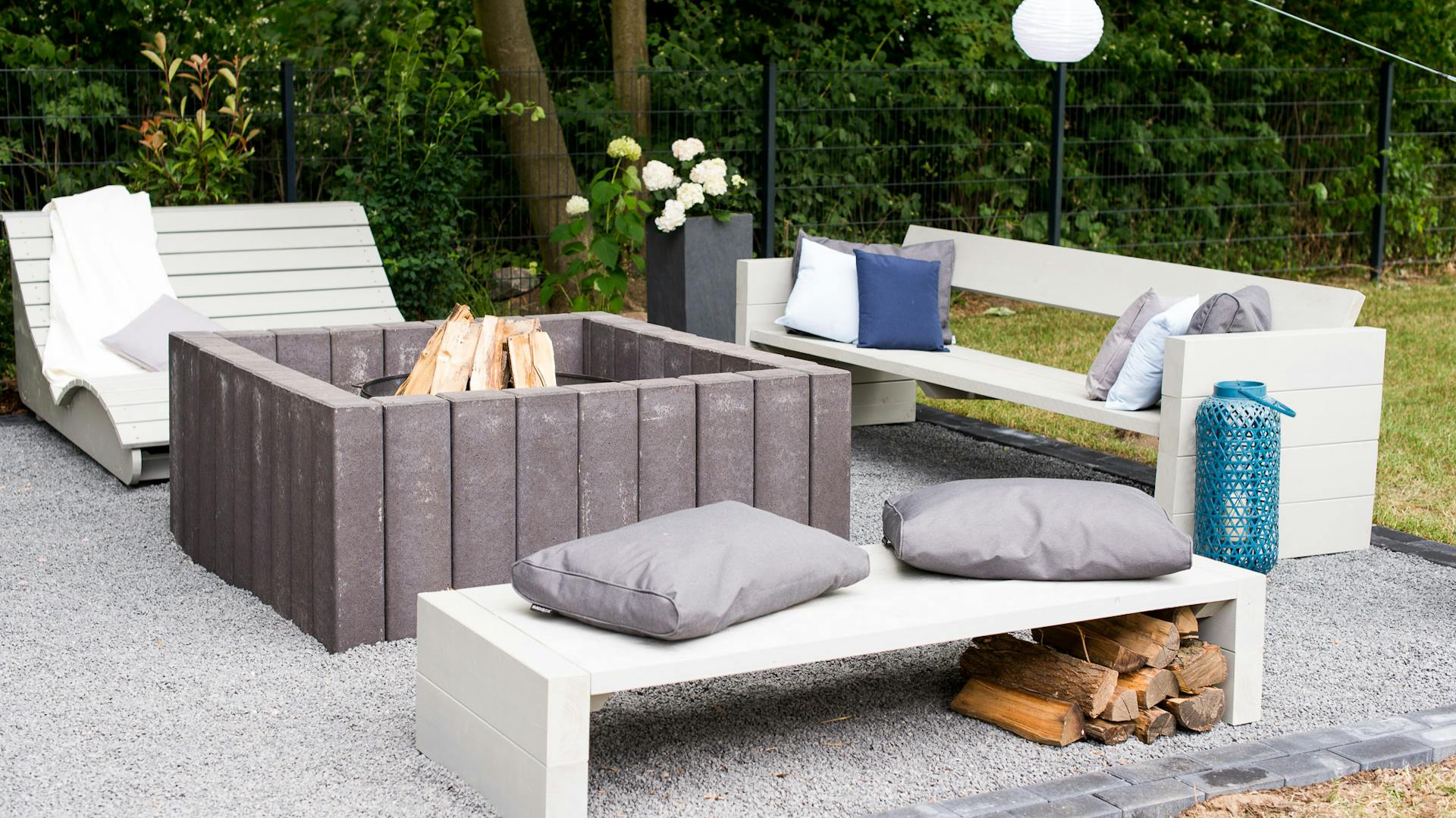 Feuerstelle mit Splittbelag und Sitzplätzen aus Selbstbaumöbeln