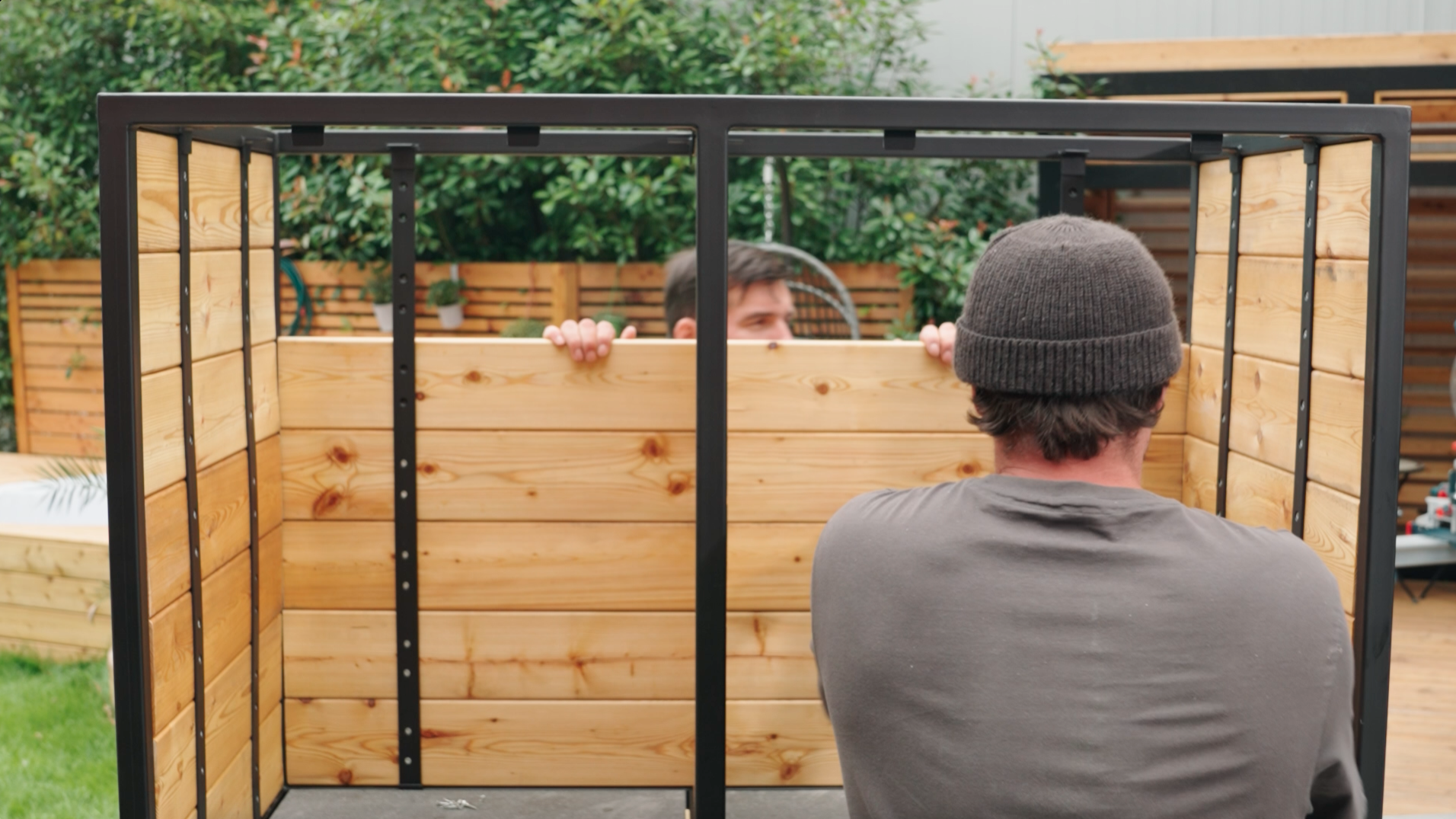 Un uomo utilizza listelli in legno per la parete posteriore della cucina esterna.