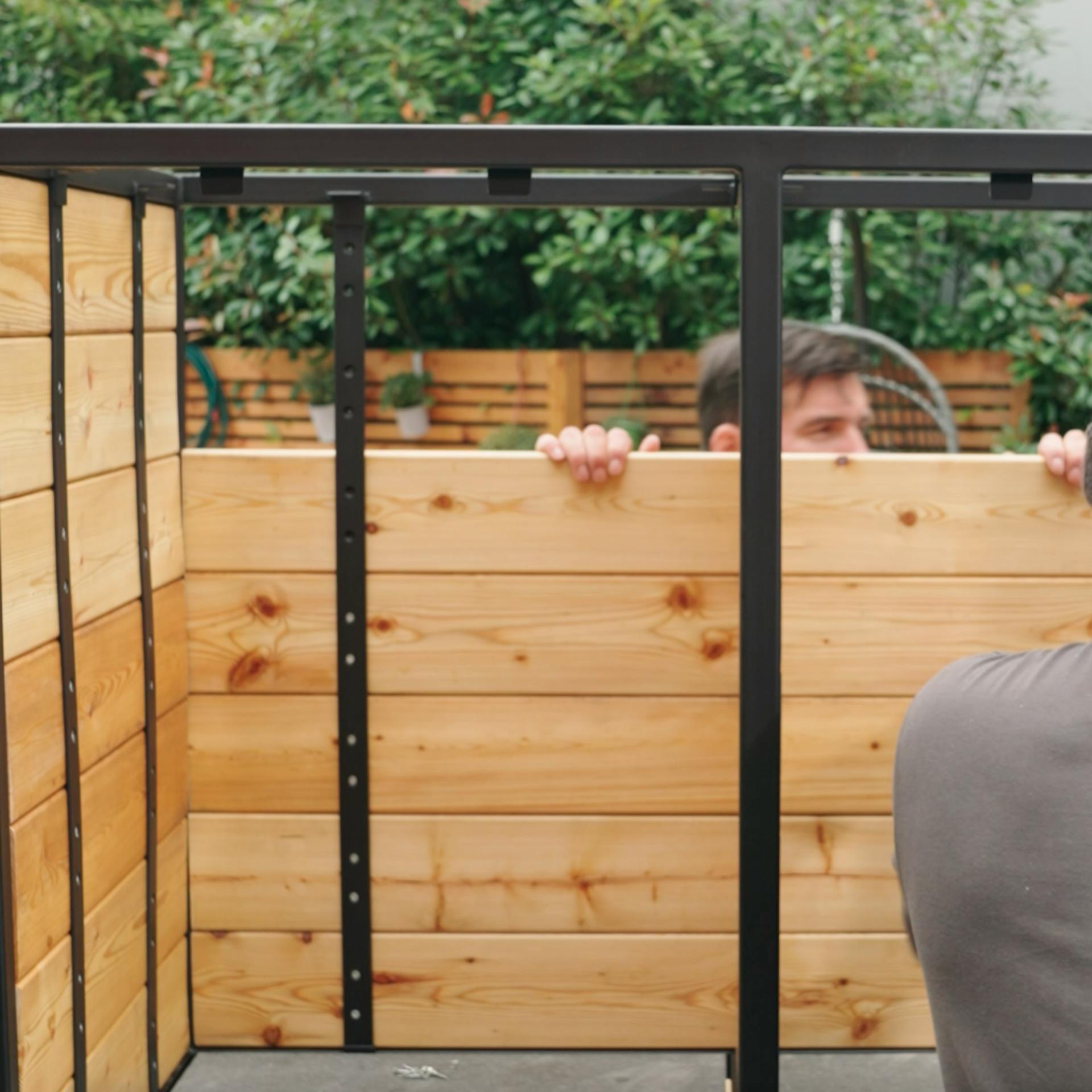 Un uomo utilizza listelli in legno per la parete posteriore della cucina esterna.