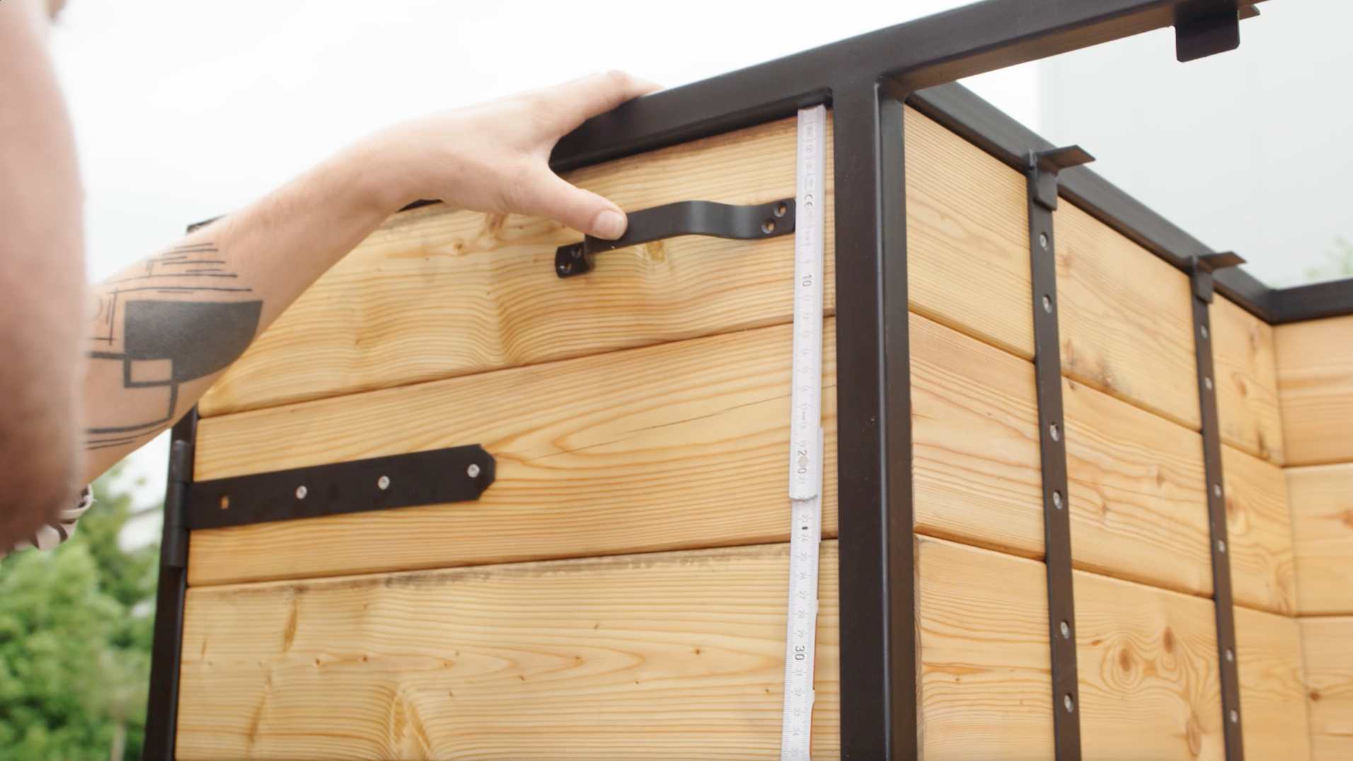 Un uomo misura con un metro pieghevole l'altezza per la maniglia della porta della cucina esterna.