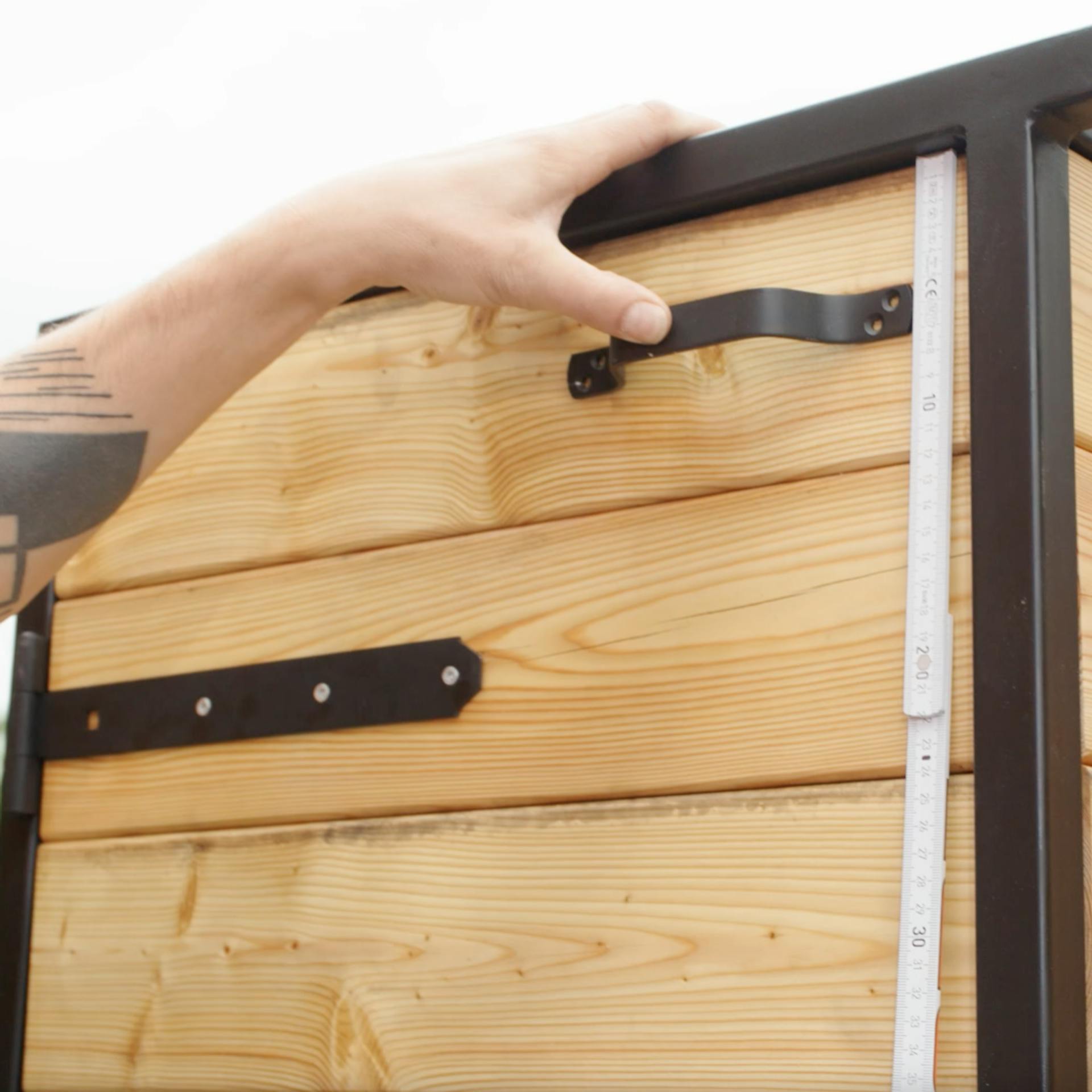 Un uomo misura con un metro pieghevole l'altezza per la maniglia della porta della cucina esterna.