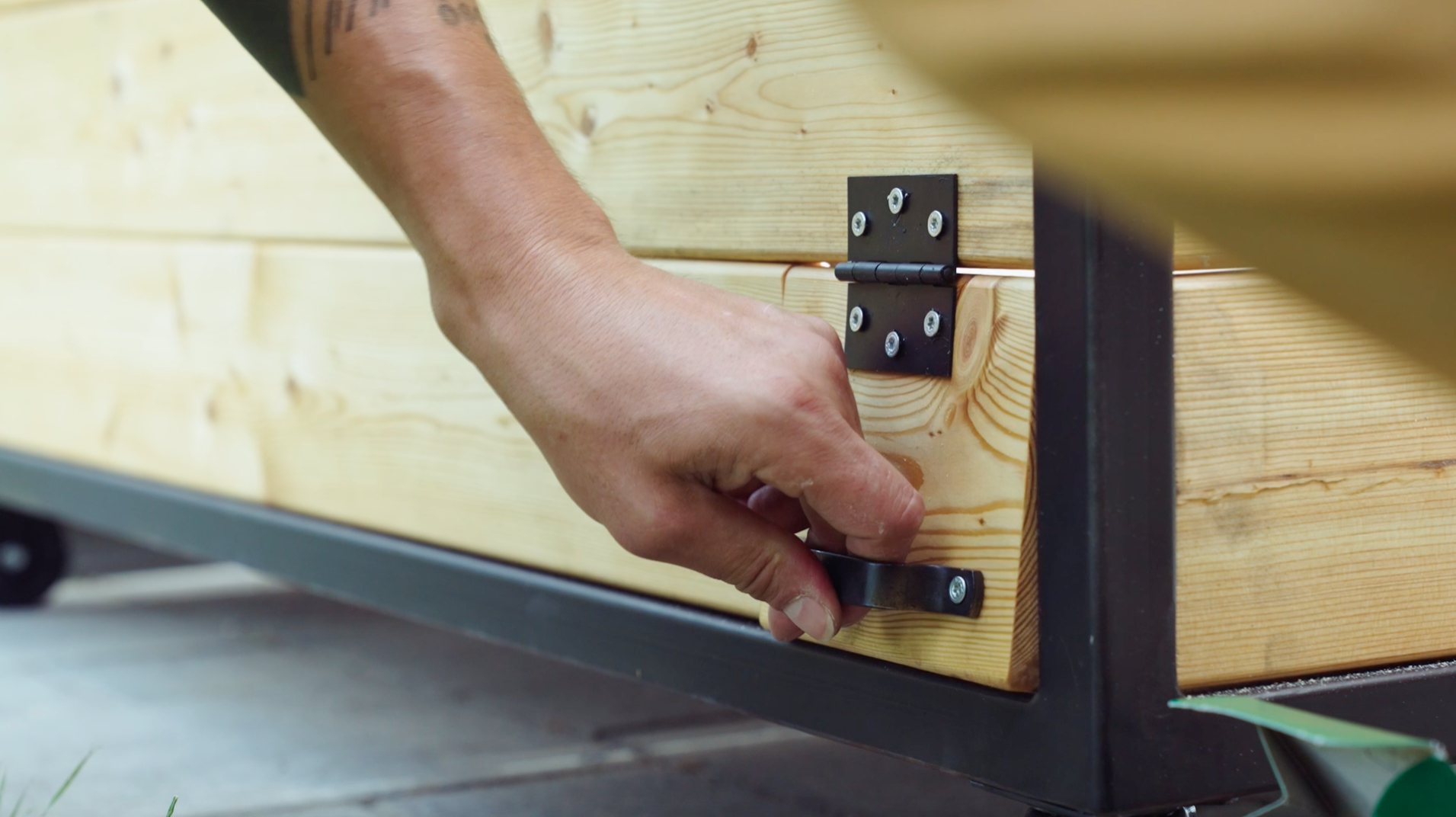 Un uomo aziona uno sportello che è stato installato sul retro della cucina esterna per collegare cavi elettrici e tubi dell'acqua.