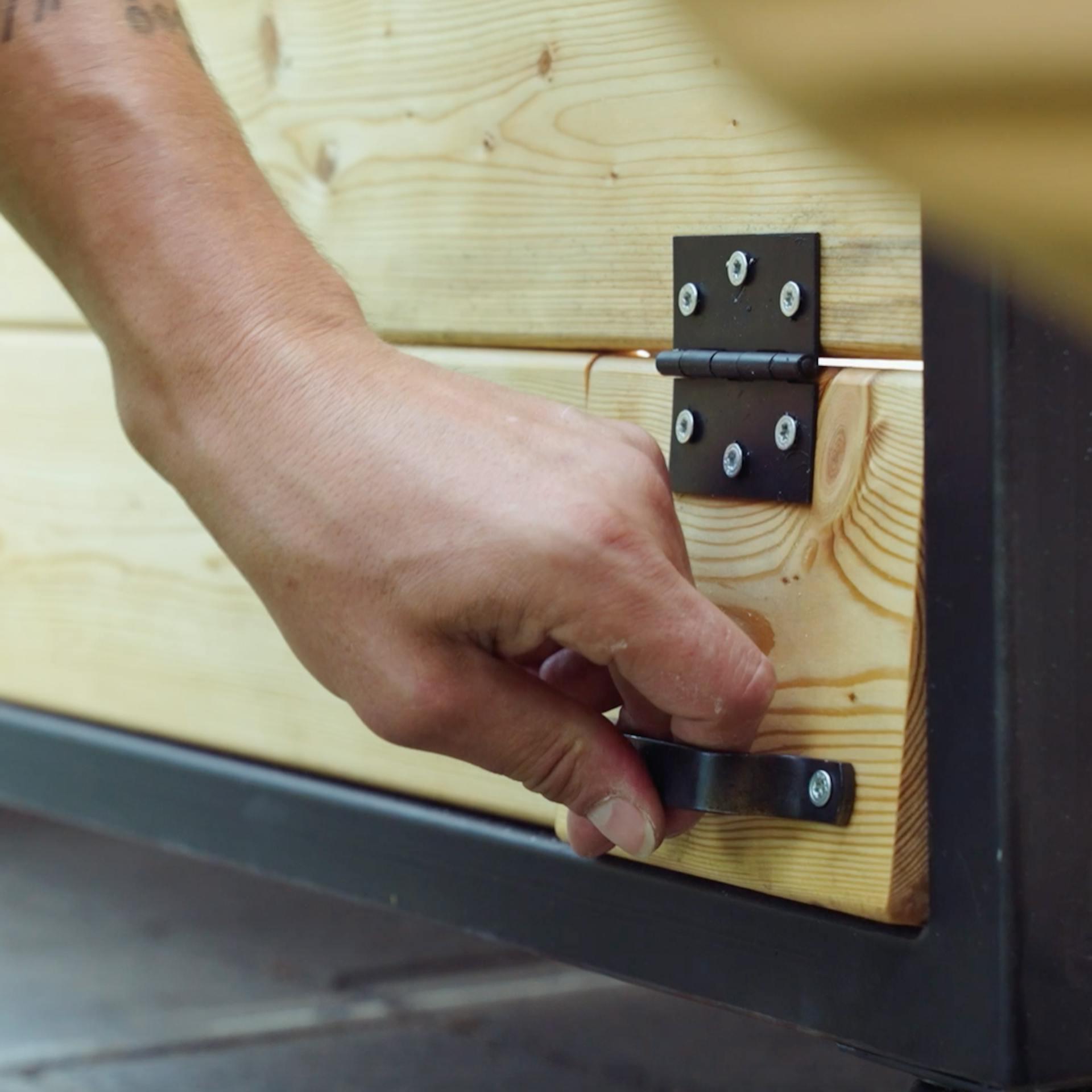 Un uomo aziona uno sportello che è stato installato sul retro della cucina esterna per collegare cavi elettrici e tubi dell'acqua.
