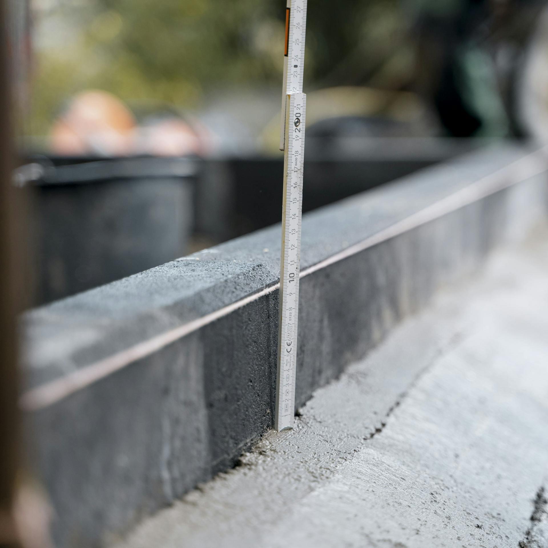 Handwerker misst mit einem Zollstock die korrekte Höhe der Randsteine aus.
