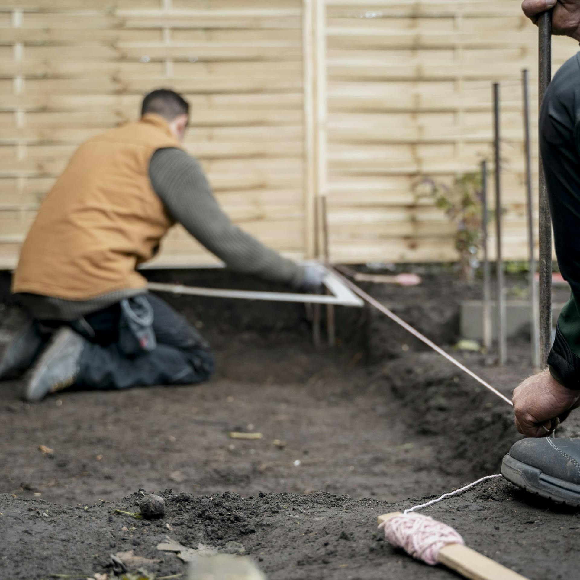 Zwei Handwerker vermessen das Schnurgerüst.