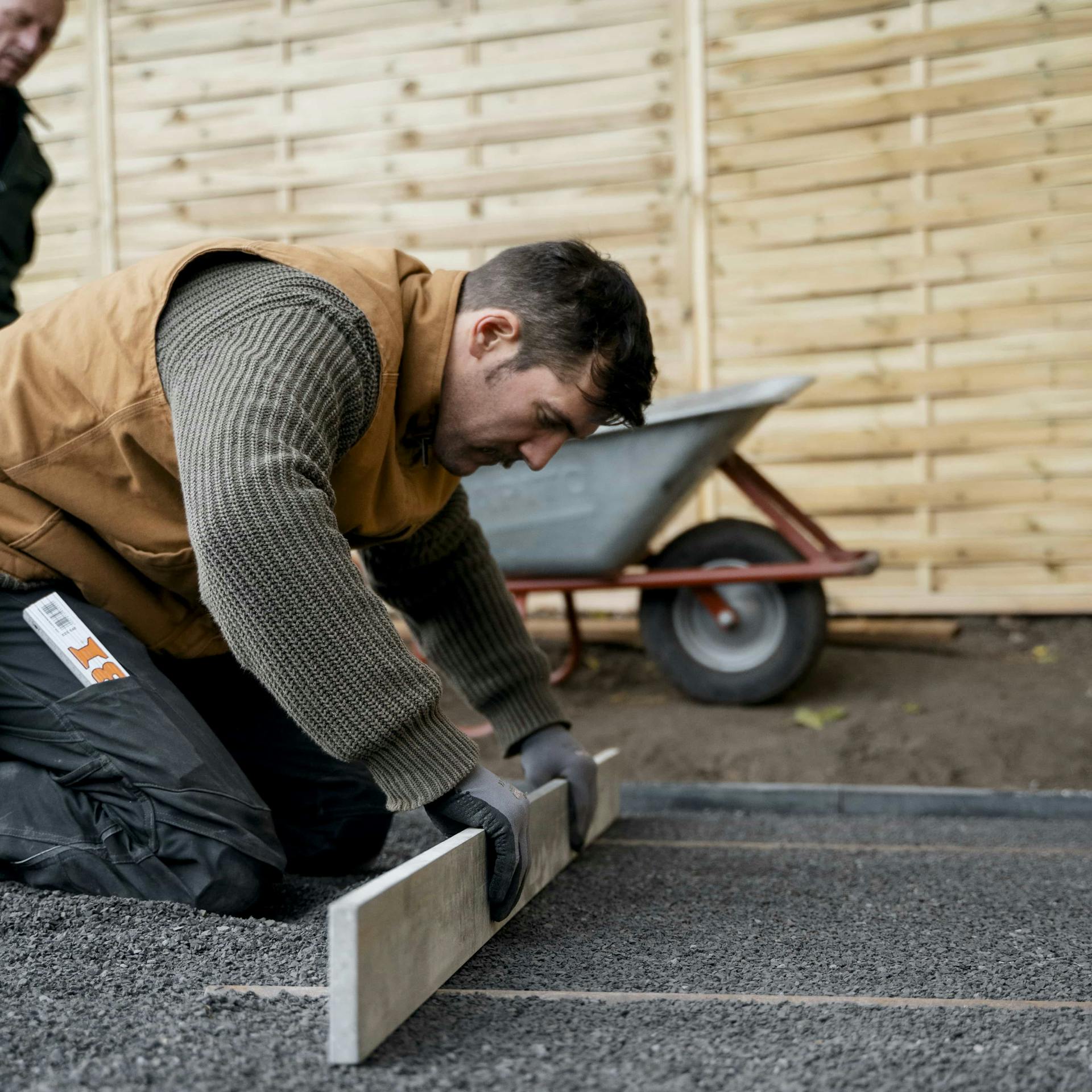 Gärtner ebnet mit einem Abziehbrett die oberste Splittschicht.