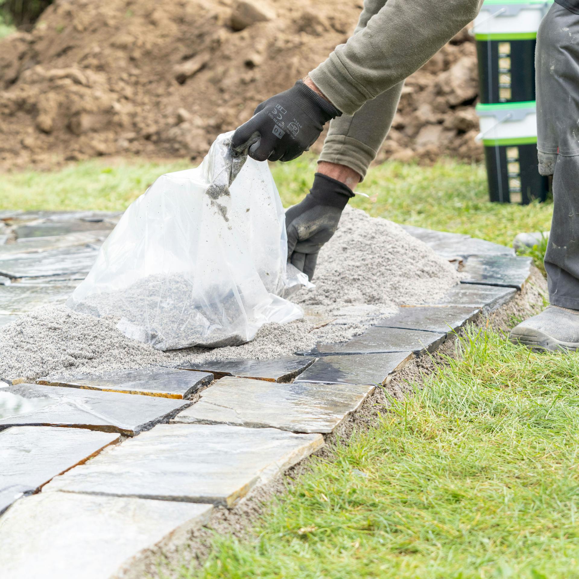 Muž sype škárovaciu maltu na polygonálne dosky