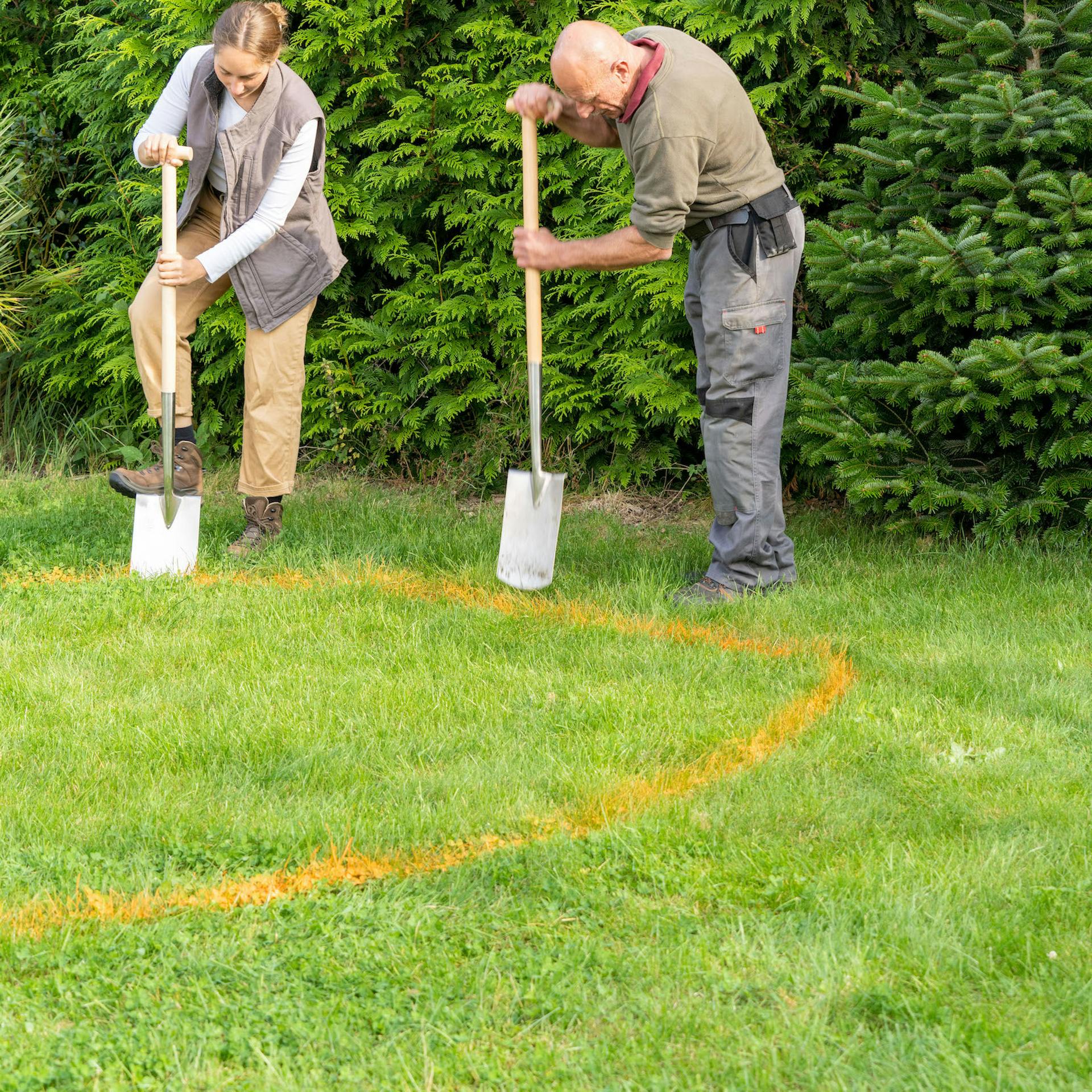 Dve osoby rýľujú na trávnatej ploche