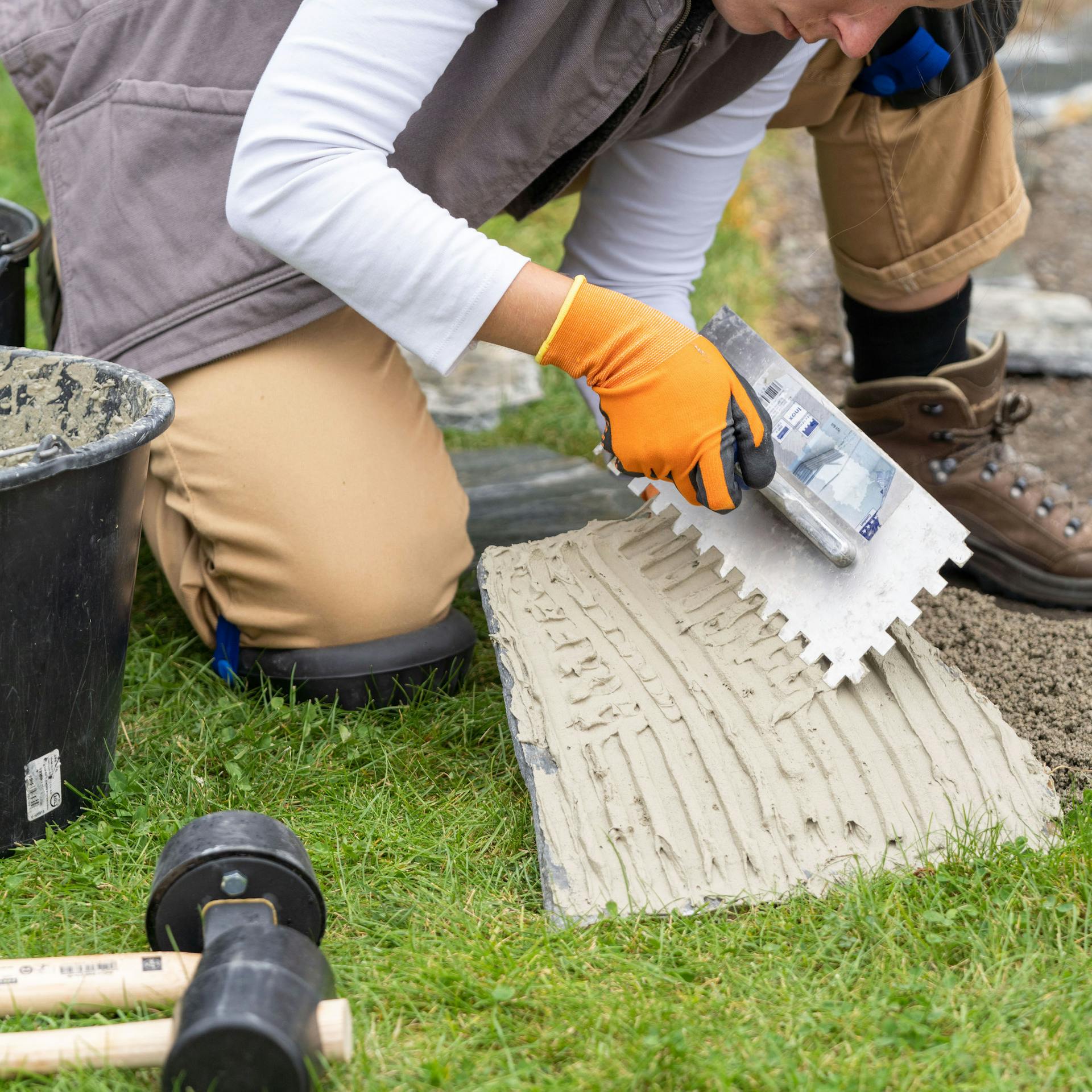 Žena nanáša kontaktný kal zúbkovaným hladidlom na polygonálnu dosku