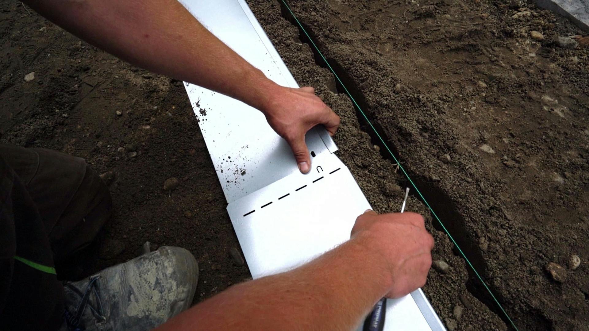 Heimwerker setzt zwei Elemente für Rasenkante aus Metall zusammen