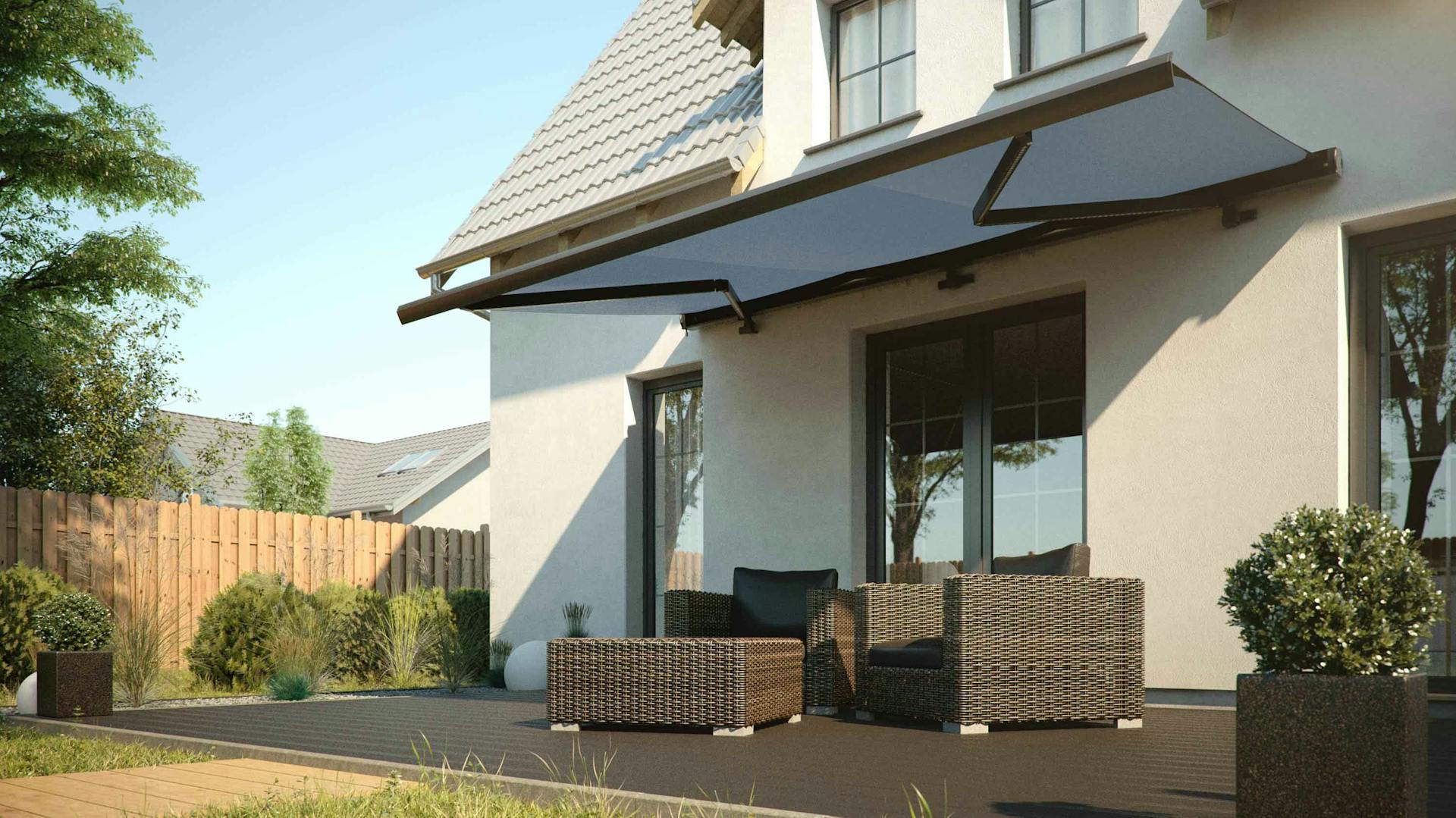 Terrazza con pavimento scuro, mobili da giardino in polyrattan scuro, bossi in vaso e una tenda da sole.
