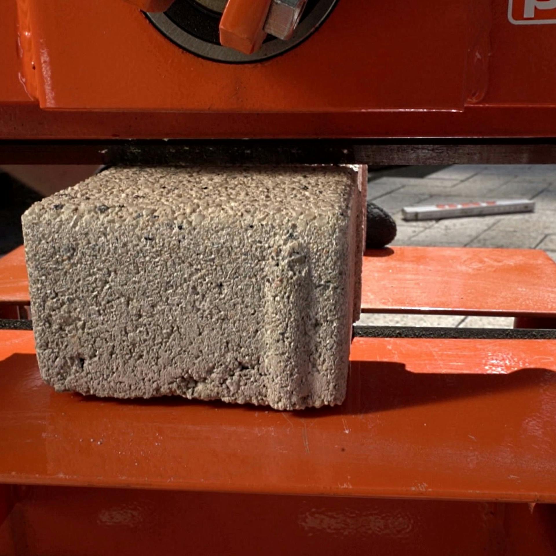 Ein Pflasterstein liegt unter der Schneide eines Steinknackers