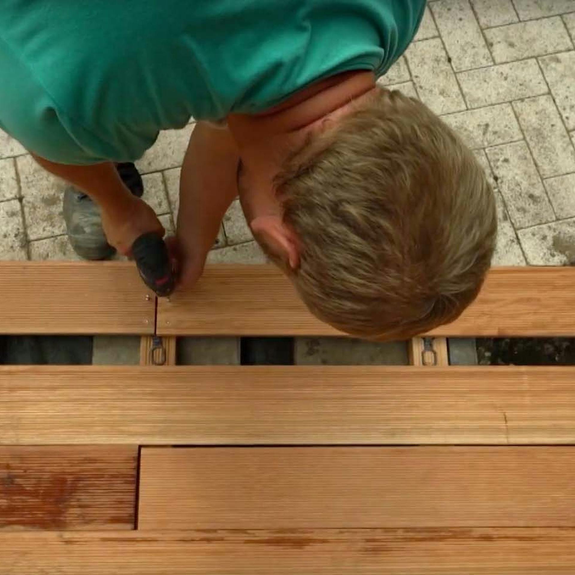 Heimwerker verschraubt Holzdielen beim Terrassenbau