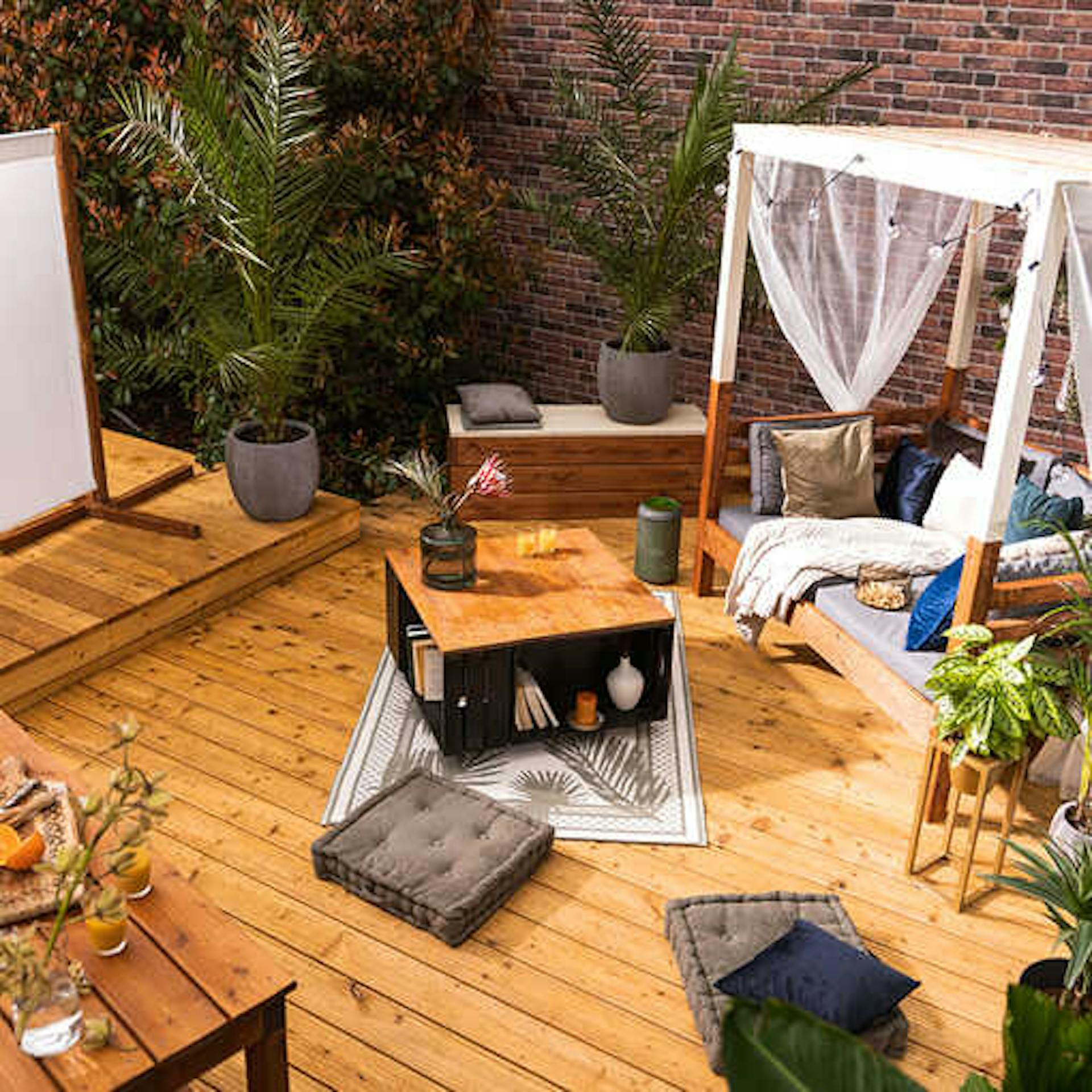 Eine Terrasse auf der eine Leinwand vor die Sonneninsel Helena platziert wurde und zwischen den beiden eine Bank Alfred und ein Couchtisch Vierfach stehen.