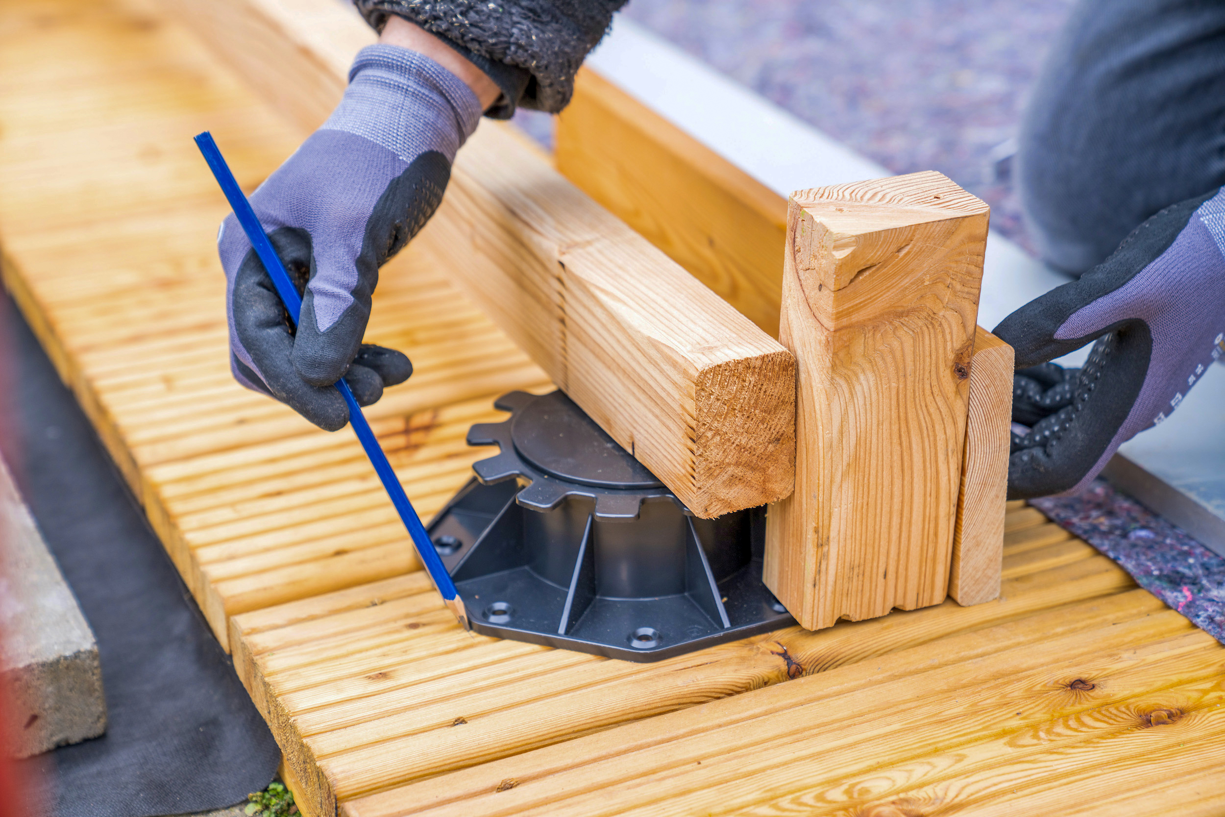 Una mano traccia la posizione di un piede di regolazione su una terrazza.