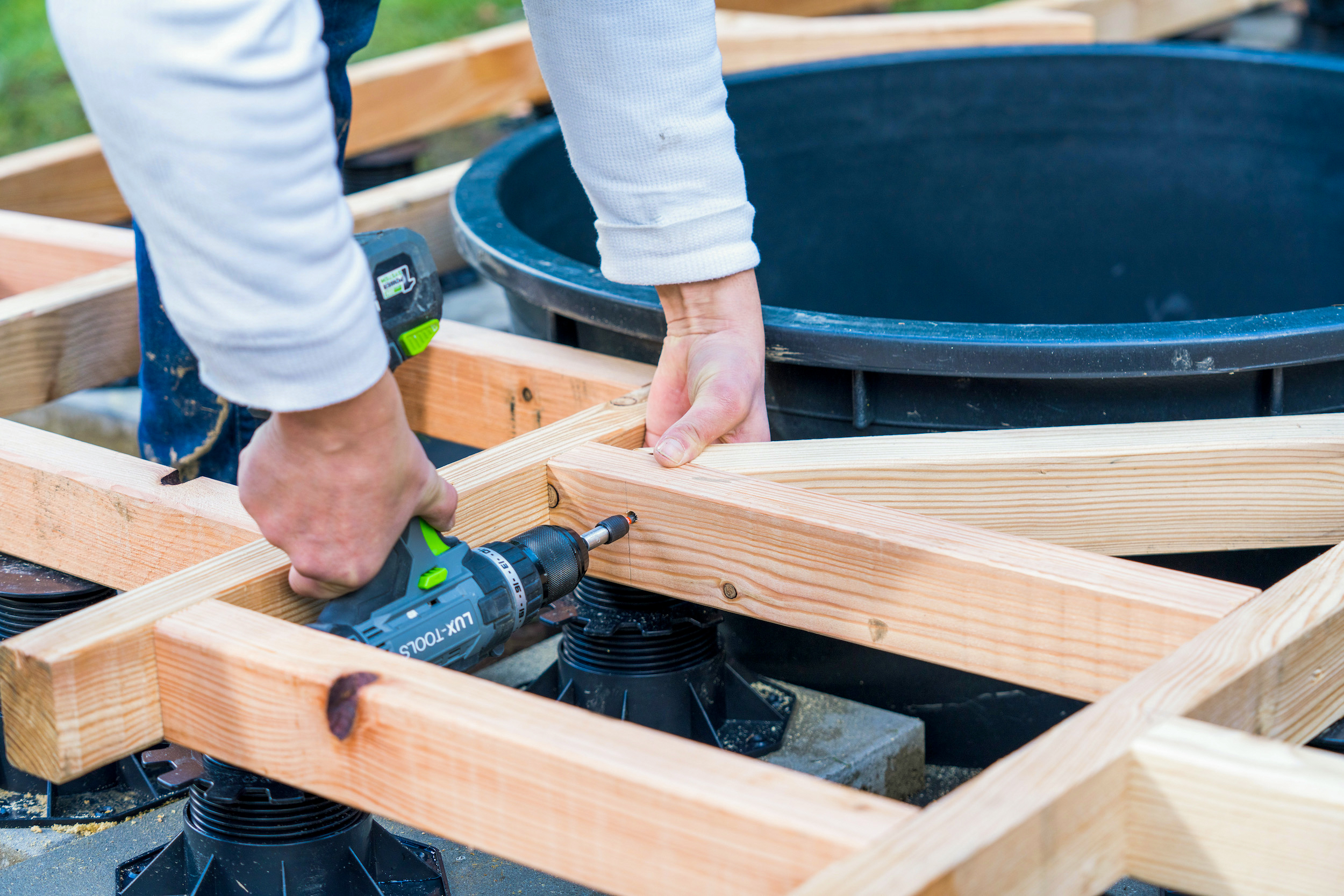 Due mani avvitano una barra trasversale accanto a una vasca per stagni.