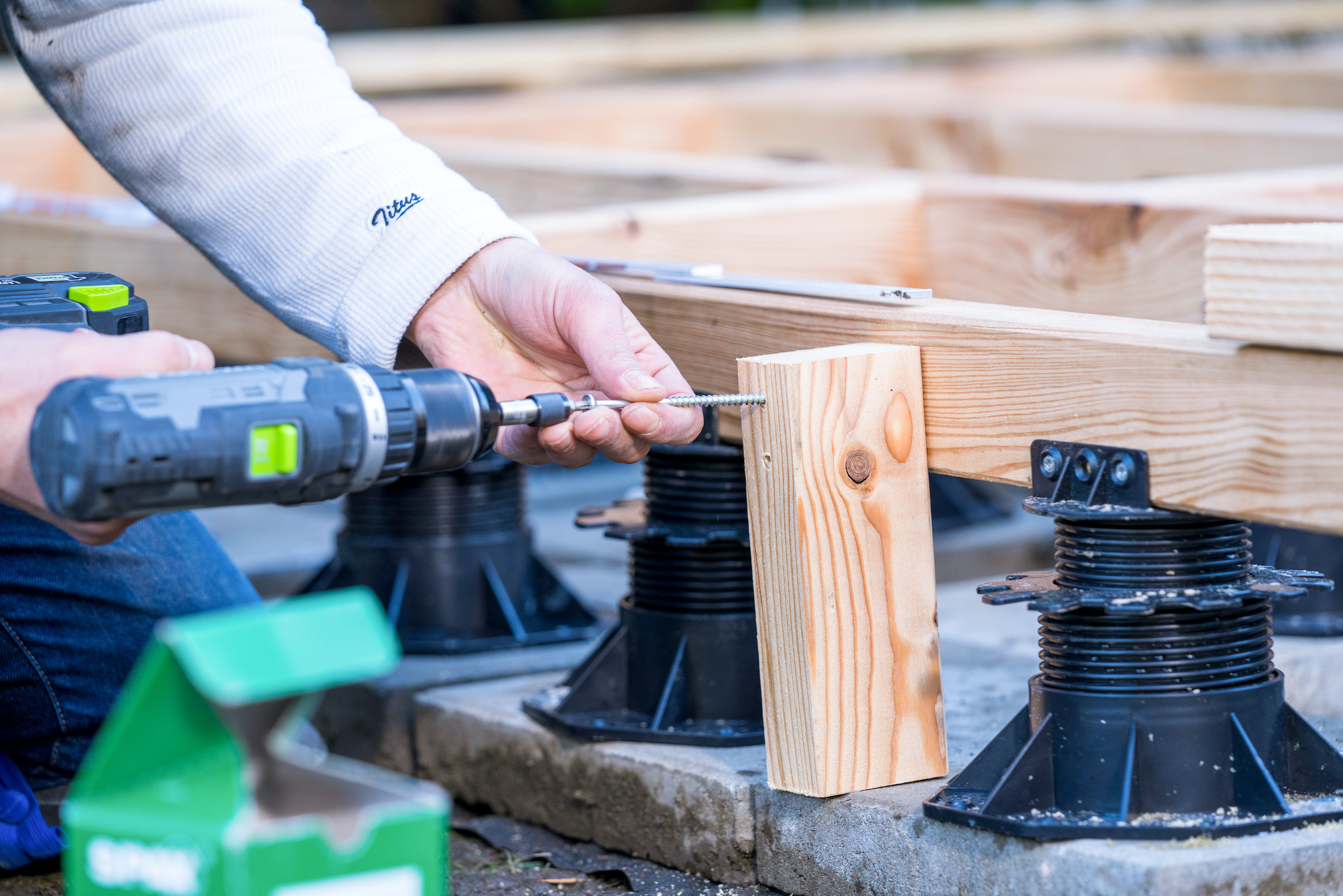 Mani avvitano saldamente un palo di legno a una trave di legno
