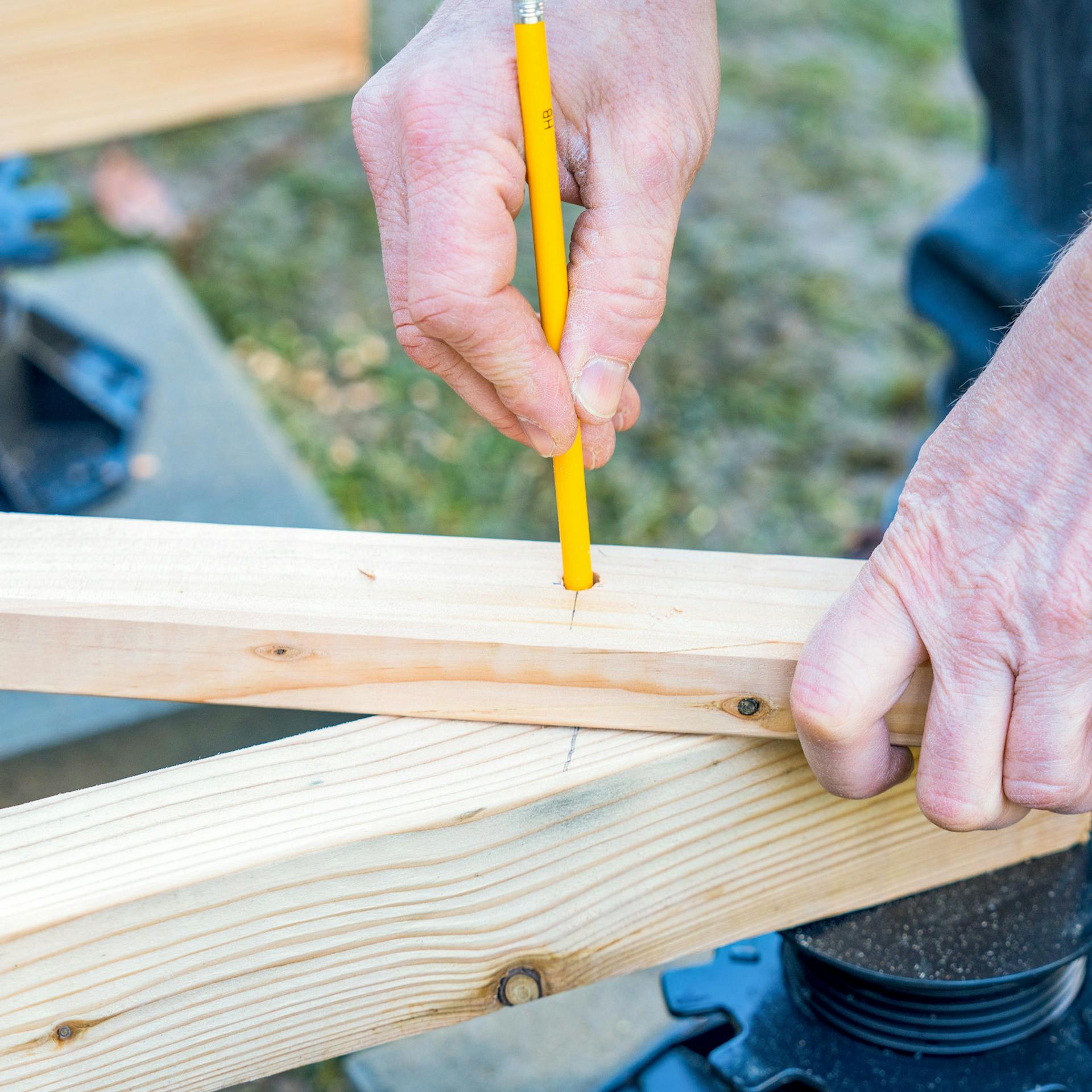 Hände zeichnen mit einem Zirkel auf einem Holzbalken
